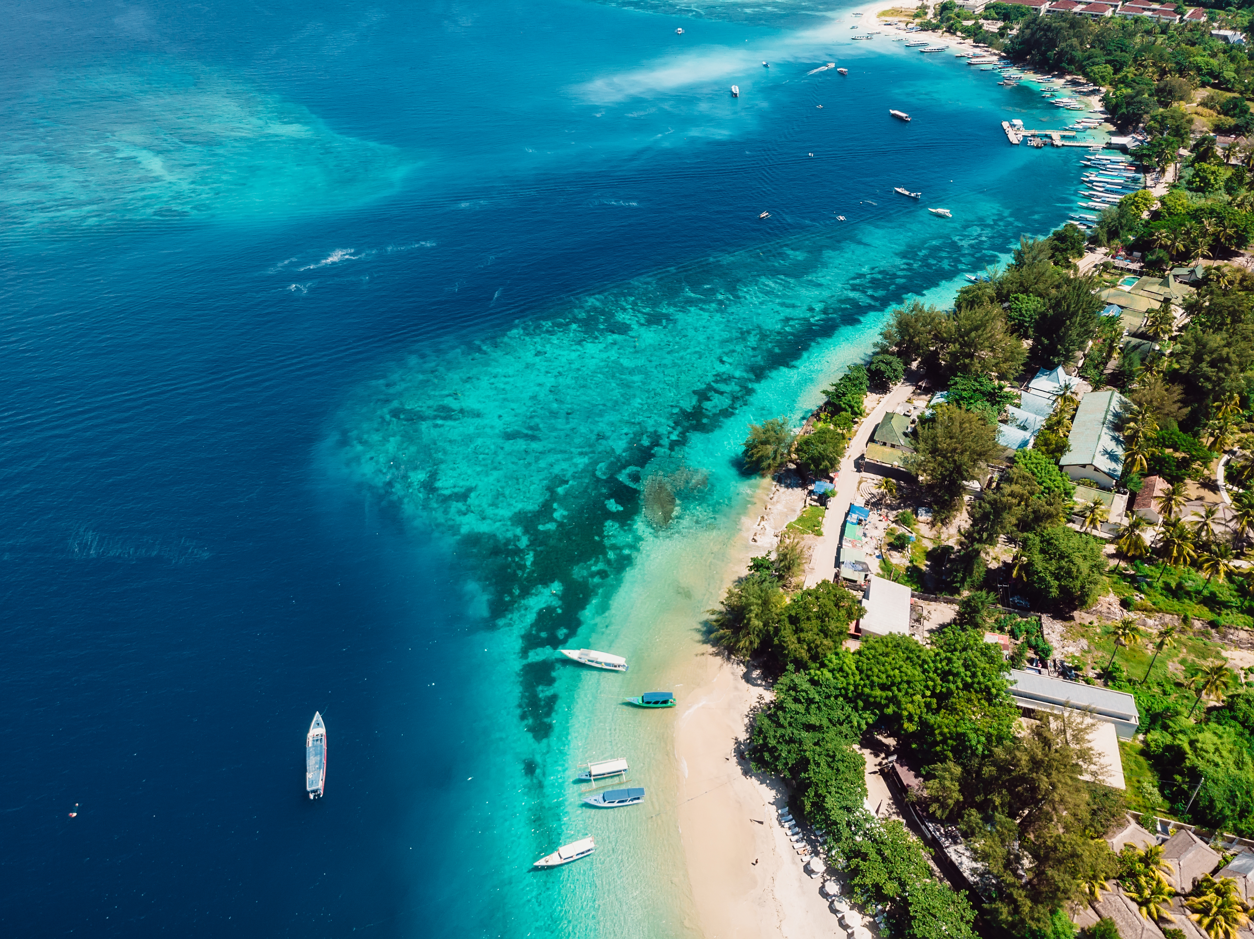 Tropical island with beach, boats and turquoise crystal ocean, aerial view. 