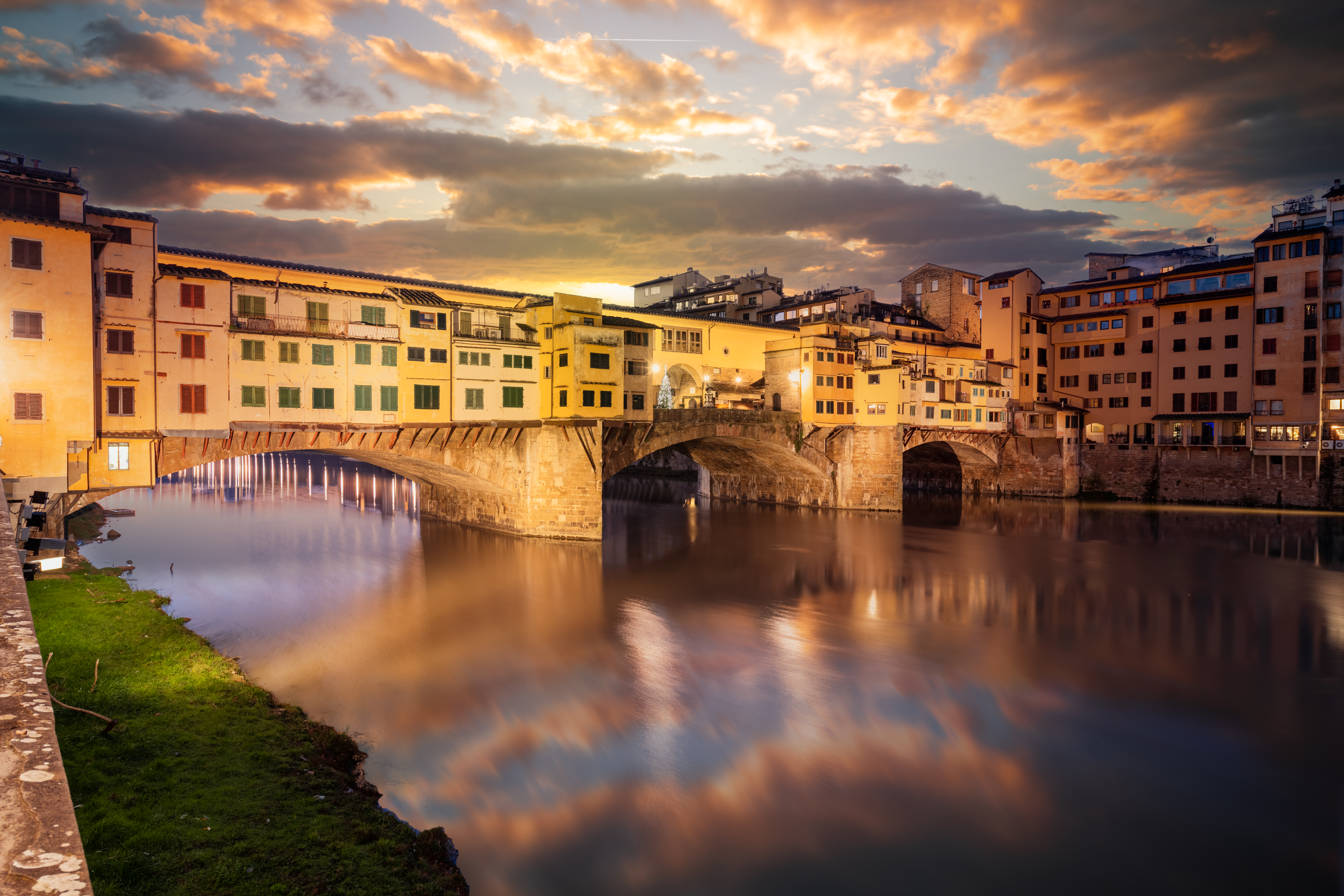 The Ponte Vecchio Bridge crossing the Arno River at twilight.