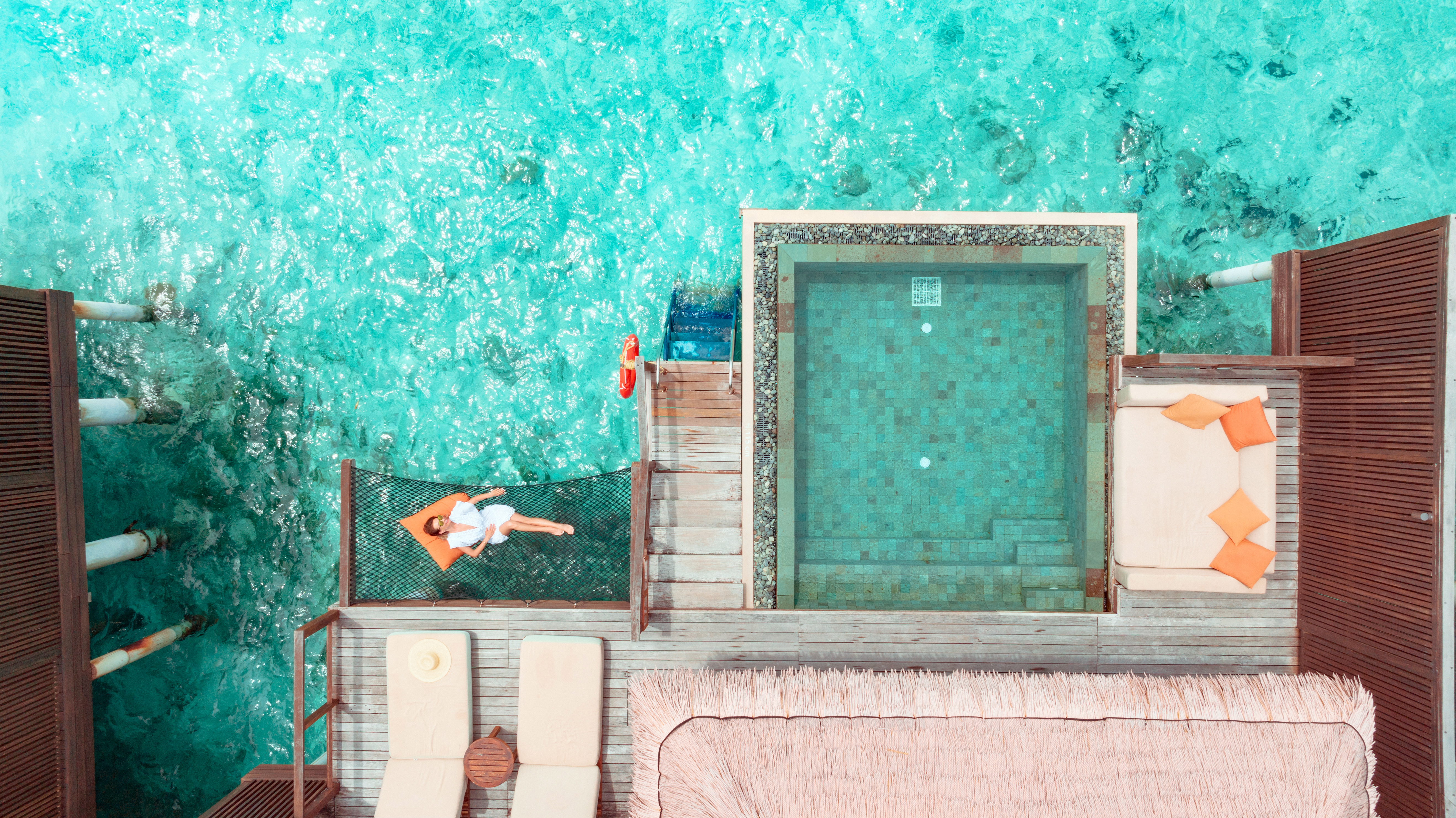 Woman lying on hammock over ocean.