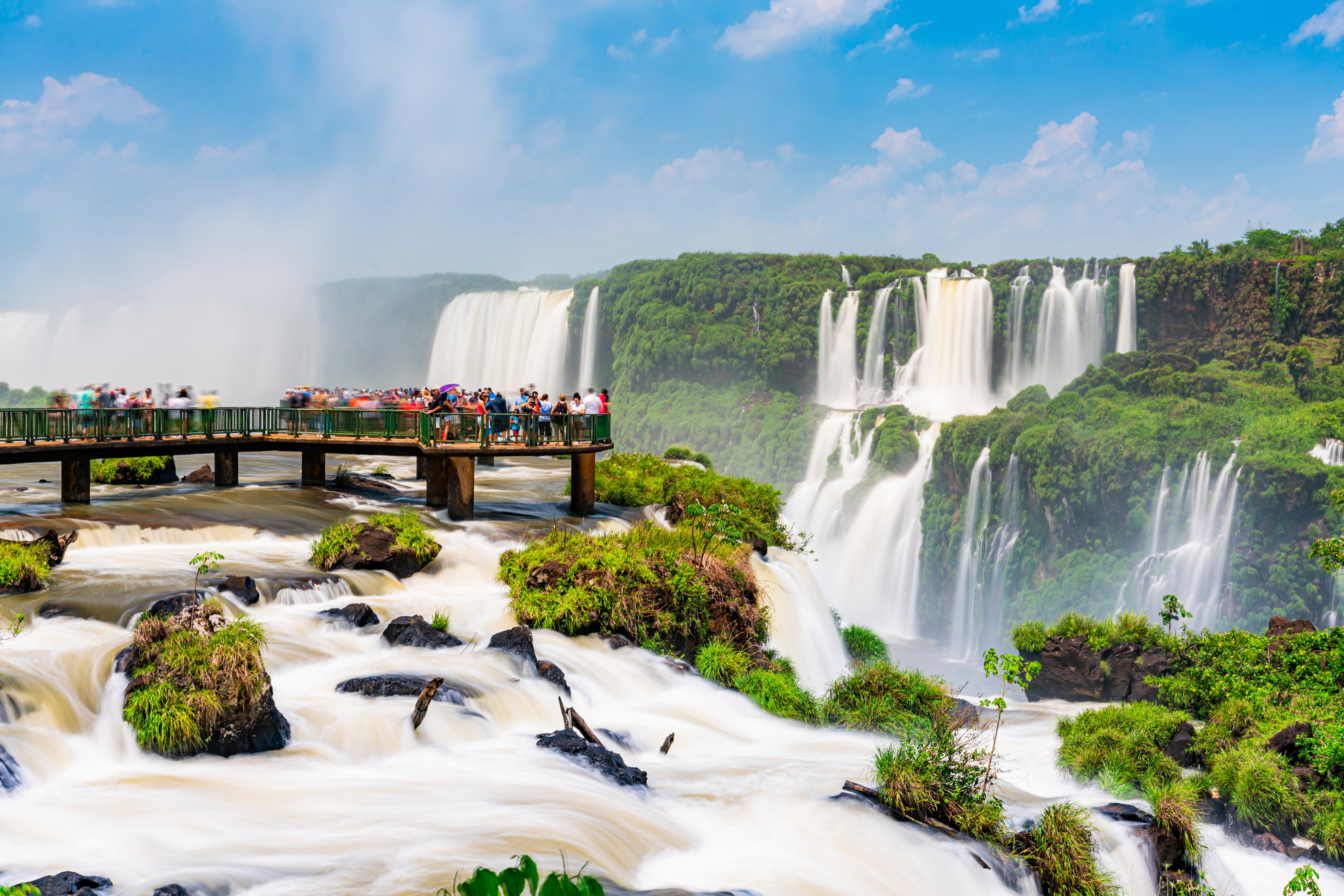 Tourists enjoying the Iguaçu Falls, Foz do Iguaçu, Parana, Brazil on the footbridge into the water on a sunny day