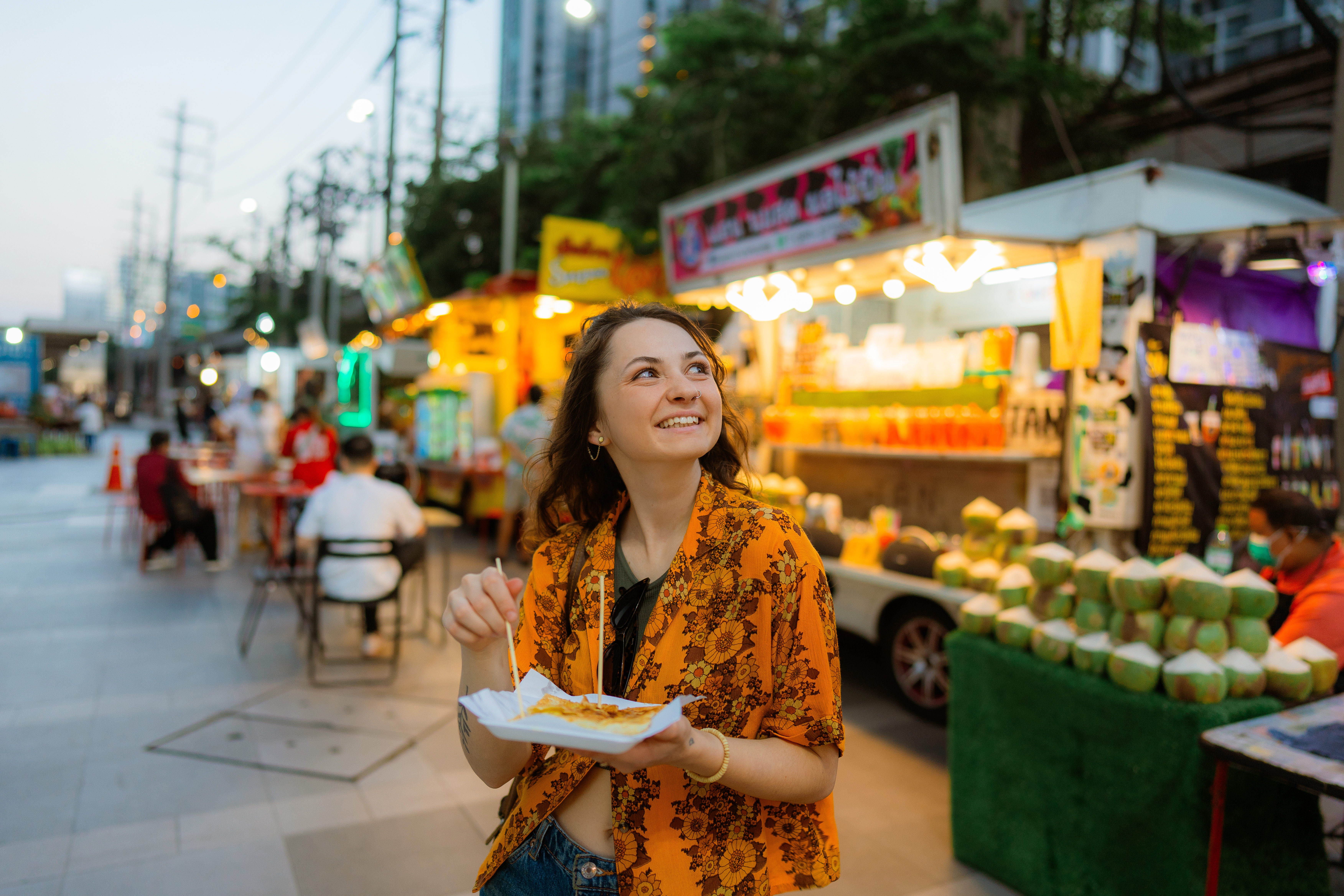 Cheerful woman eating thai pancakes (roti) on night market in Bangkok