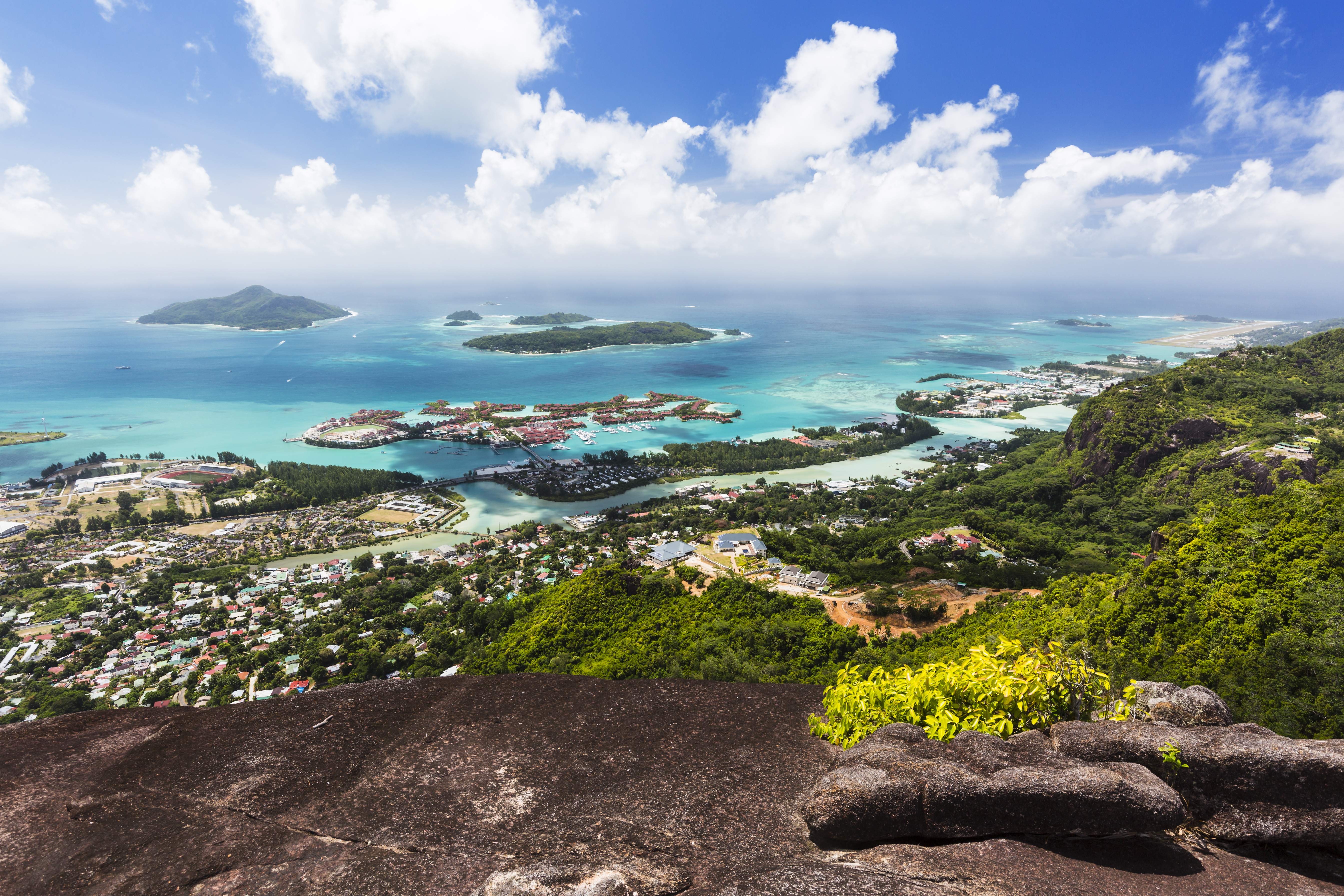 Mount Copolia over the east of Mahe, Seychelles with the capital Victoria and Eden Island, granite rock in the foreground.