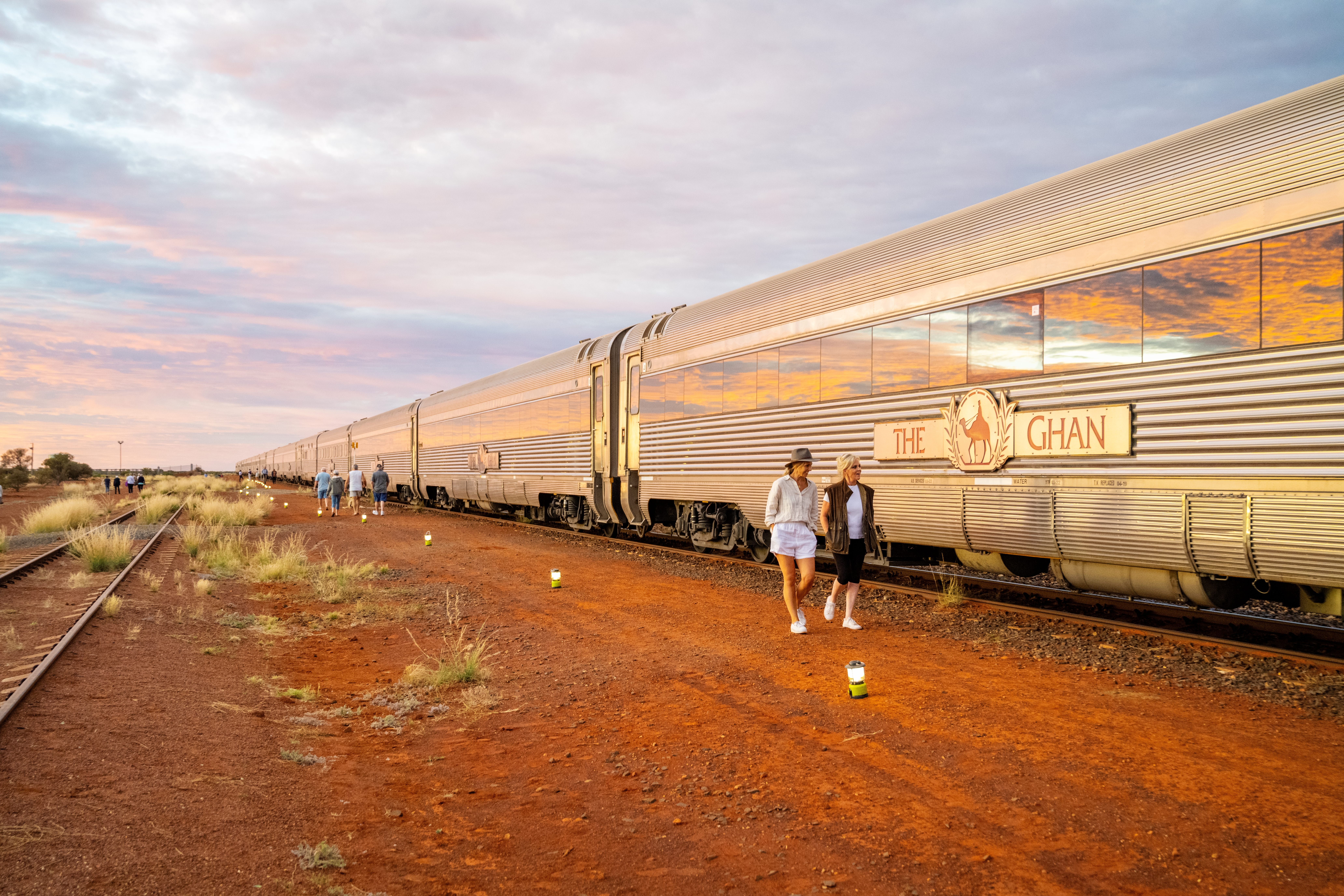Two women walking along The Ghan train stopped in its tracks in the Australian Outback at sunset in South Australia.