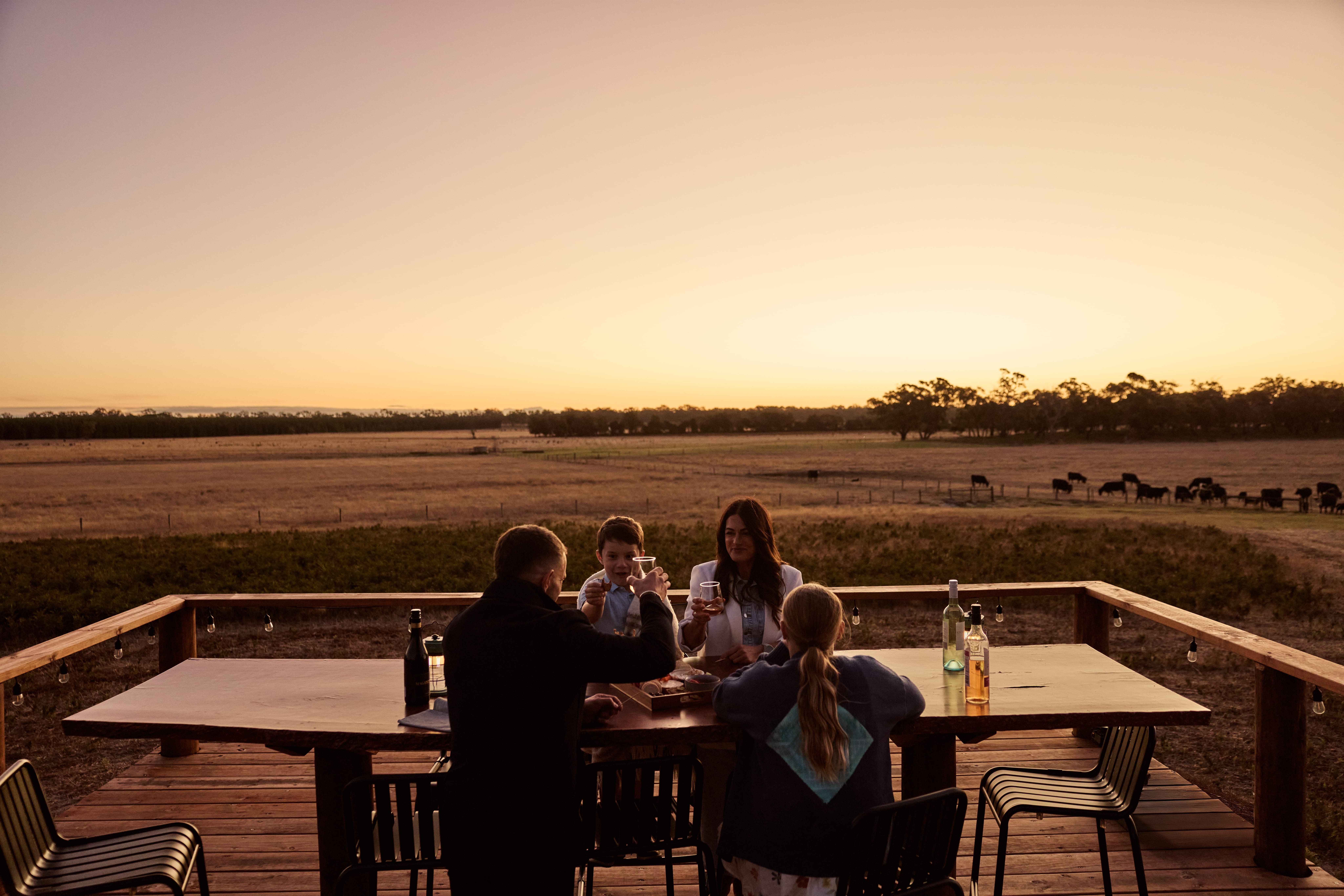 A family sharing an outdoor, sunset toast at Warrawindi Escapes on the Limestone Coast, South Australia.