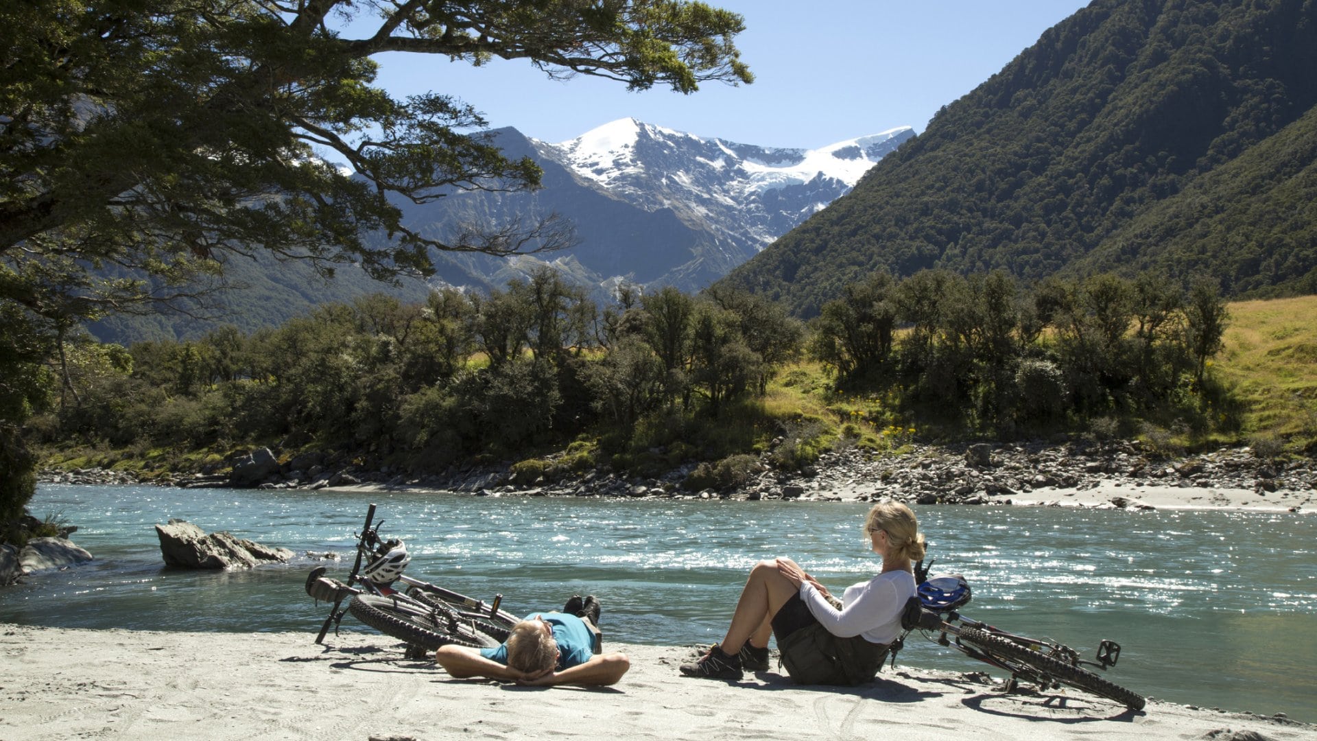  Mountain biking couple relax on river bank 