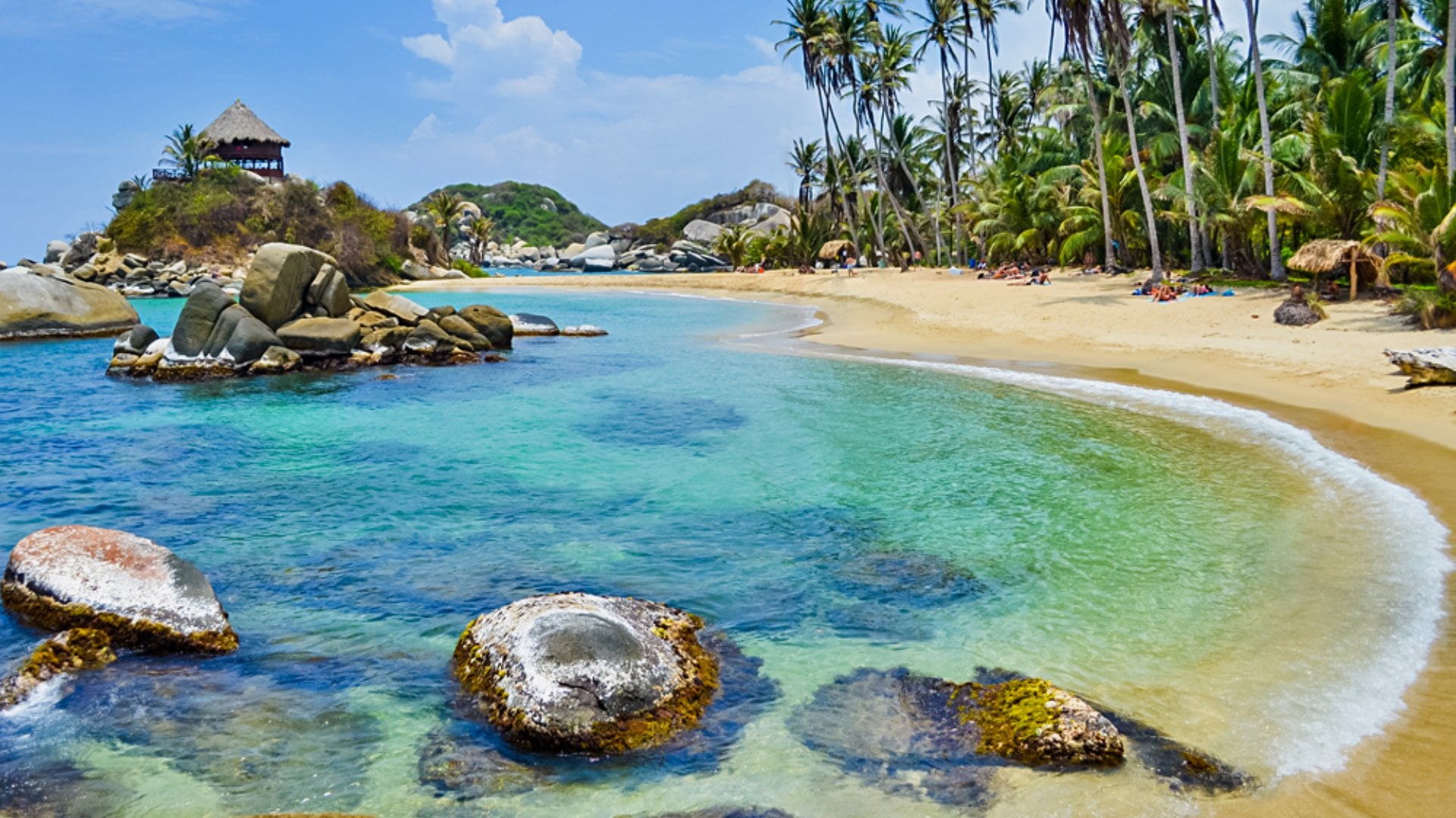 Paradise beach with white sand, palm trees and blue waters of Caribbean Sea in Tayrona National Park in Colombia