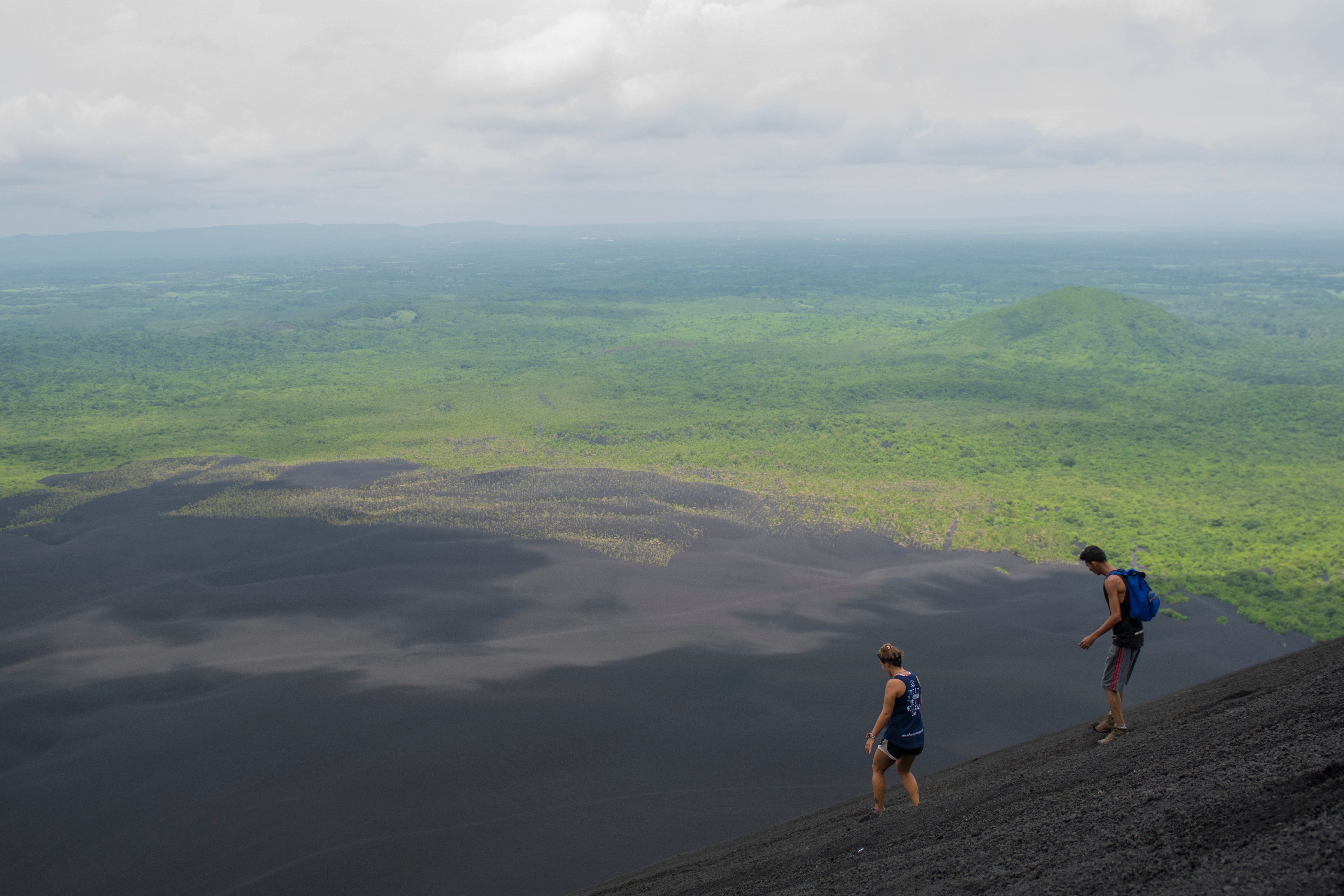 Hikers descending the black exterior of Cerro Negro, one of Central America's youngest active volcanoes.