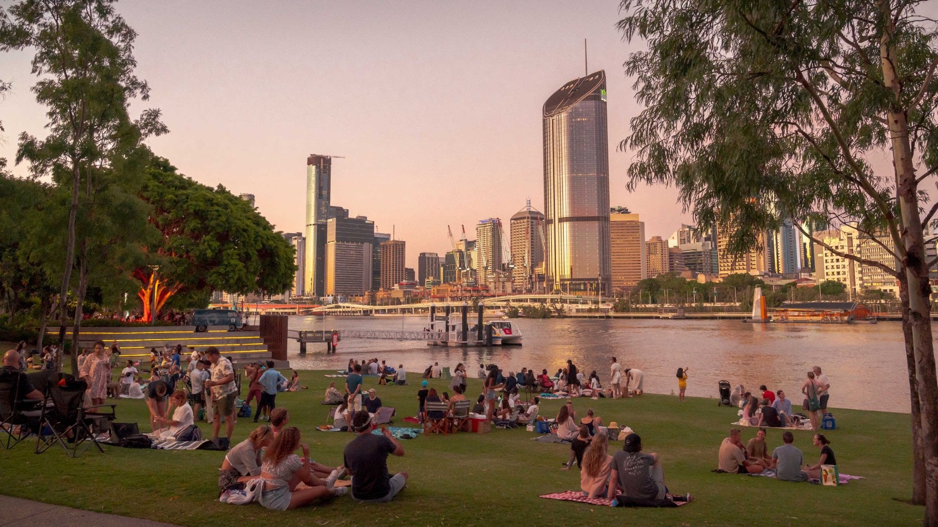 Photo of multiple groups of young adults having picnics on the shores of South Bank, Brisbane, Queensland, Australia.