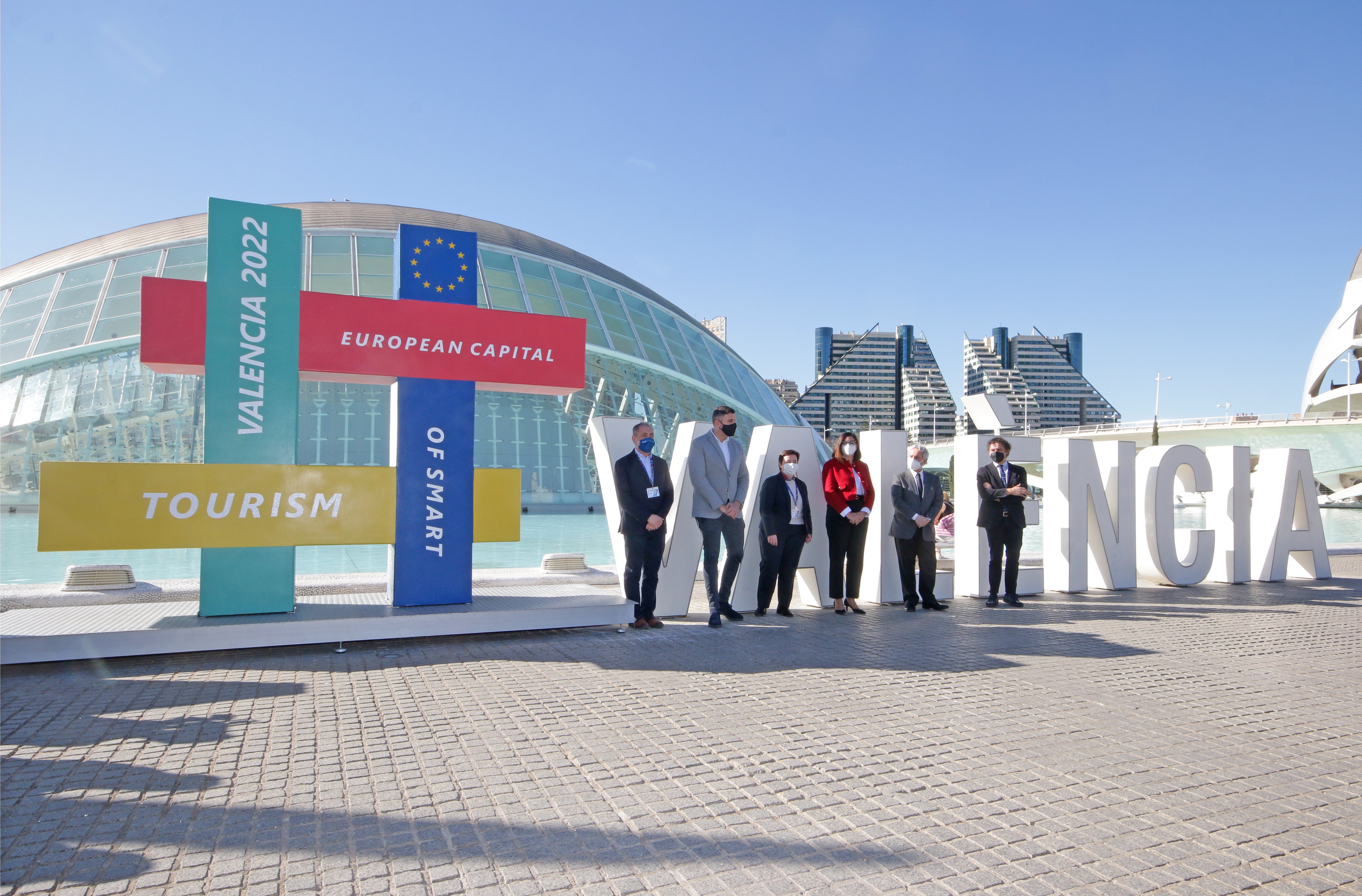 A group of officals stand in front of the Valencia sign and the 2022 European Capital of Smart Tourism sign.