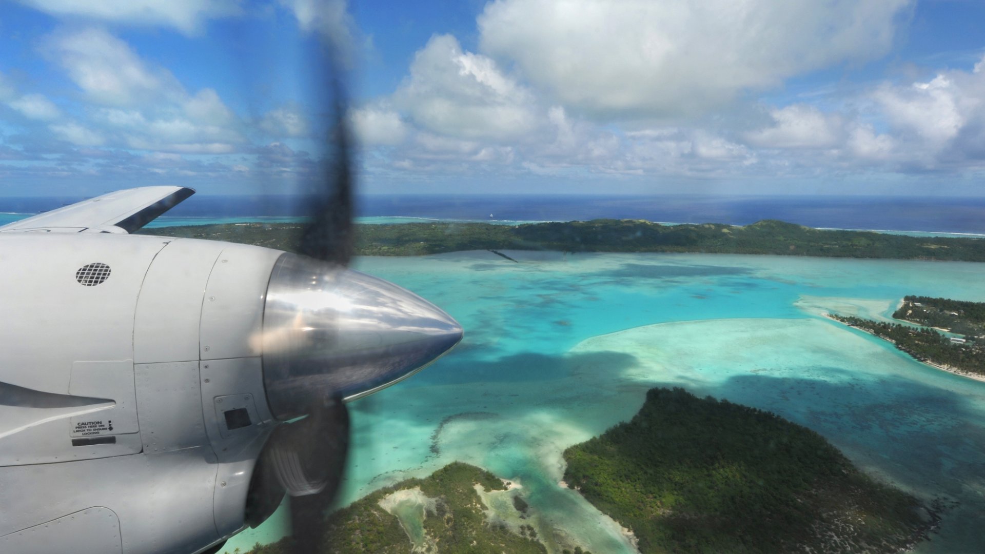 View from a plane window, over the propeller and island lagoon