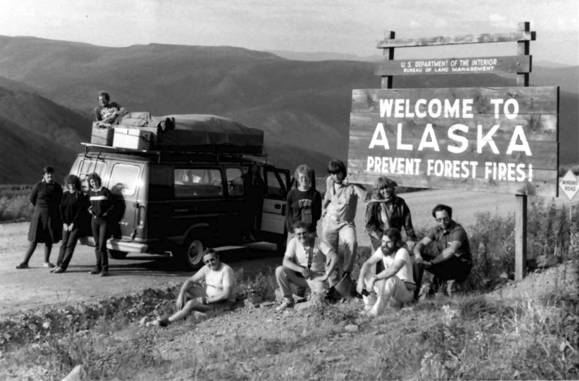 Goway camping tour group and minibus at the Welcome to Alaska sign on the Yukon–Alaska border