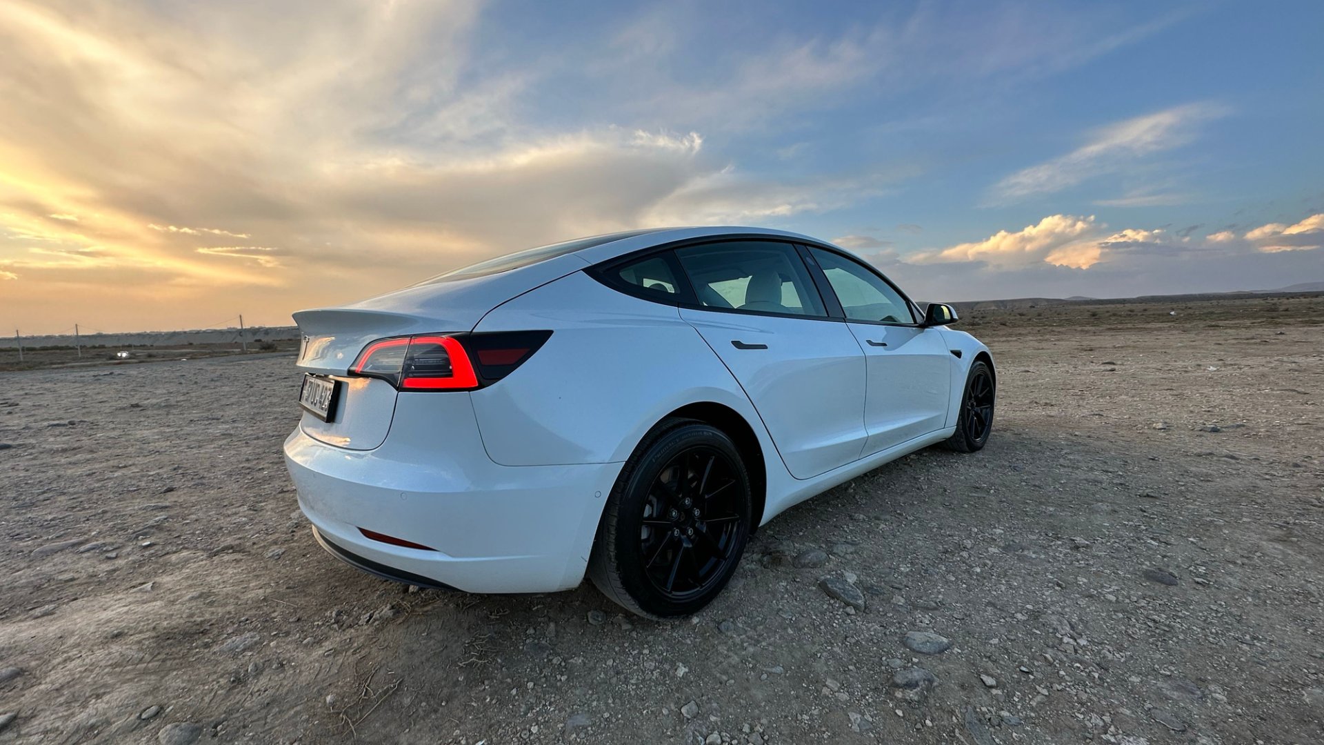White Tesla model 3 parked outdoors at sunset