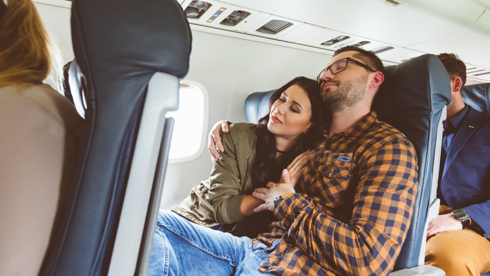Young couple traveling together by airplane. Loving man and woman on flight.