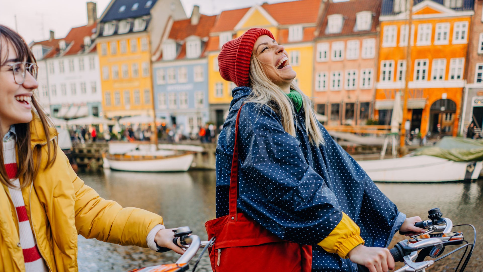 Two women riding bicycles along the canals of Copenhagen in Denmark