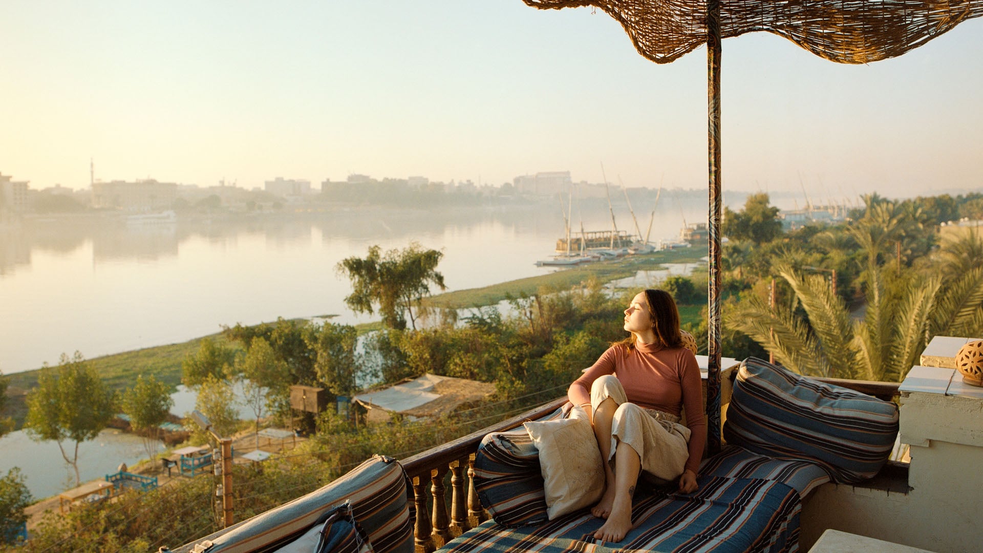 A woman relaxing on a cushion in Luxor overlooking the Nile River in Egypt