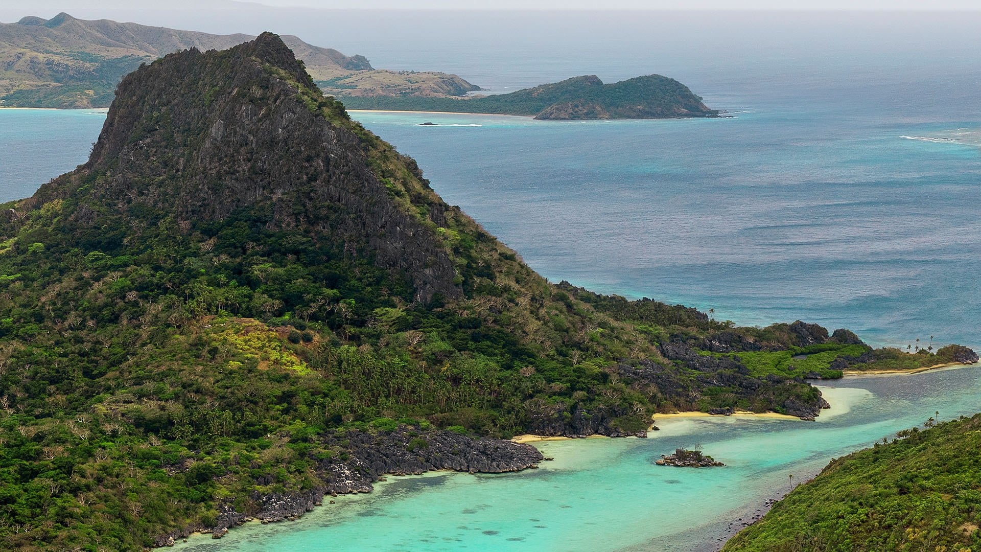 aerial view of jungle covered island and blue waters of the ocean