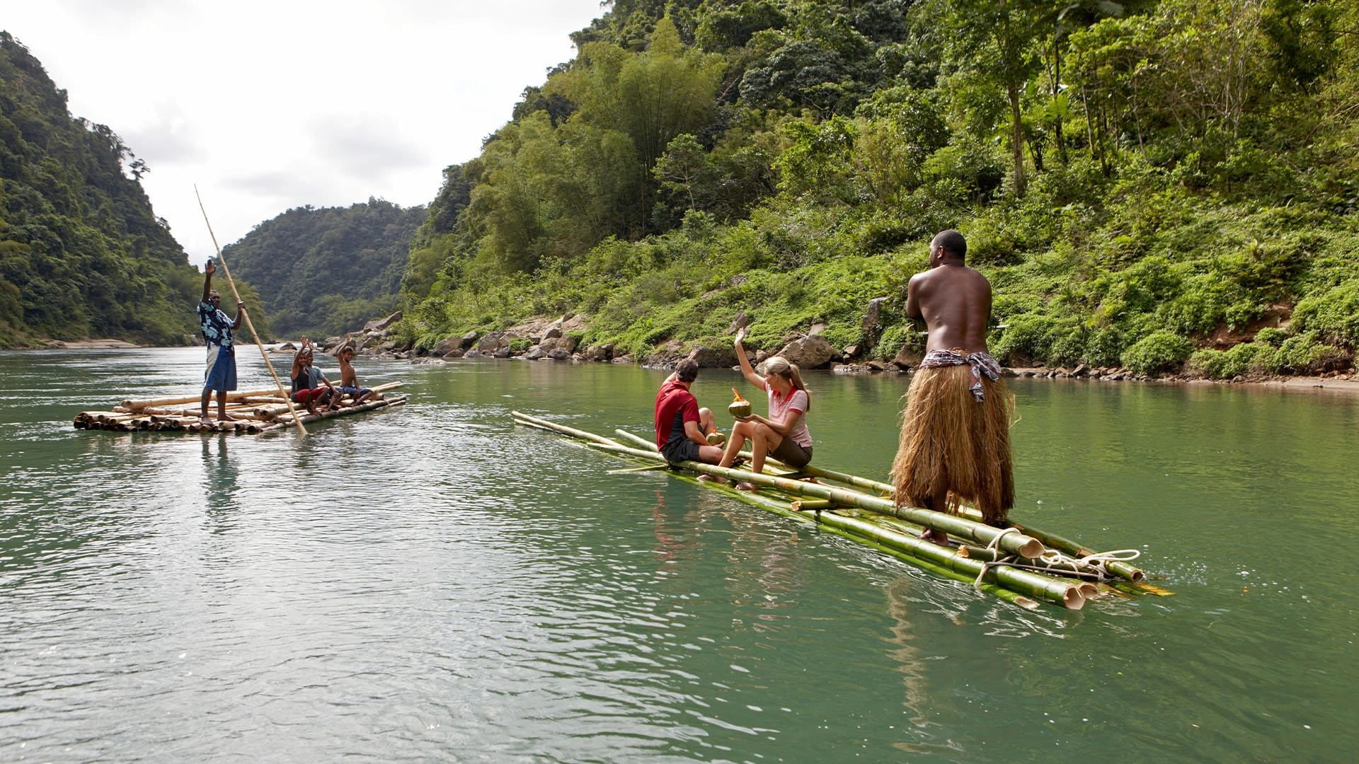 people riding bamboo rafts down a river and men in traditional dress