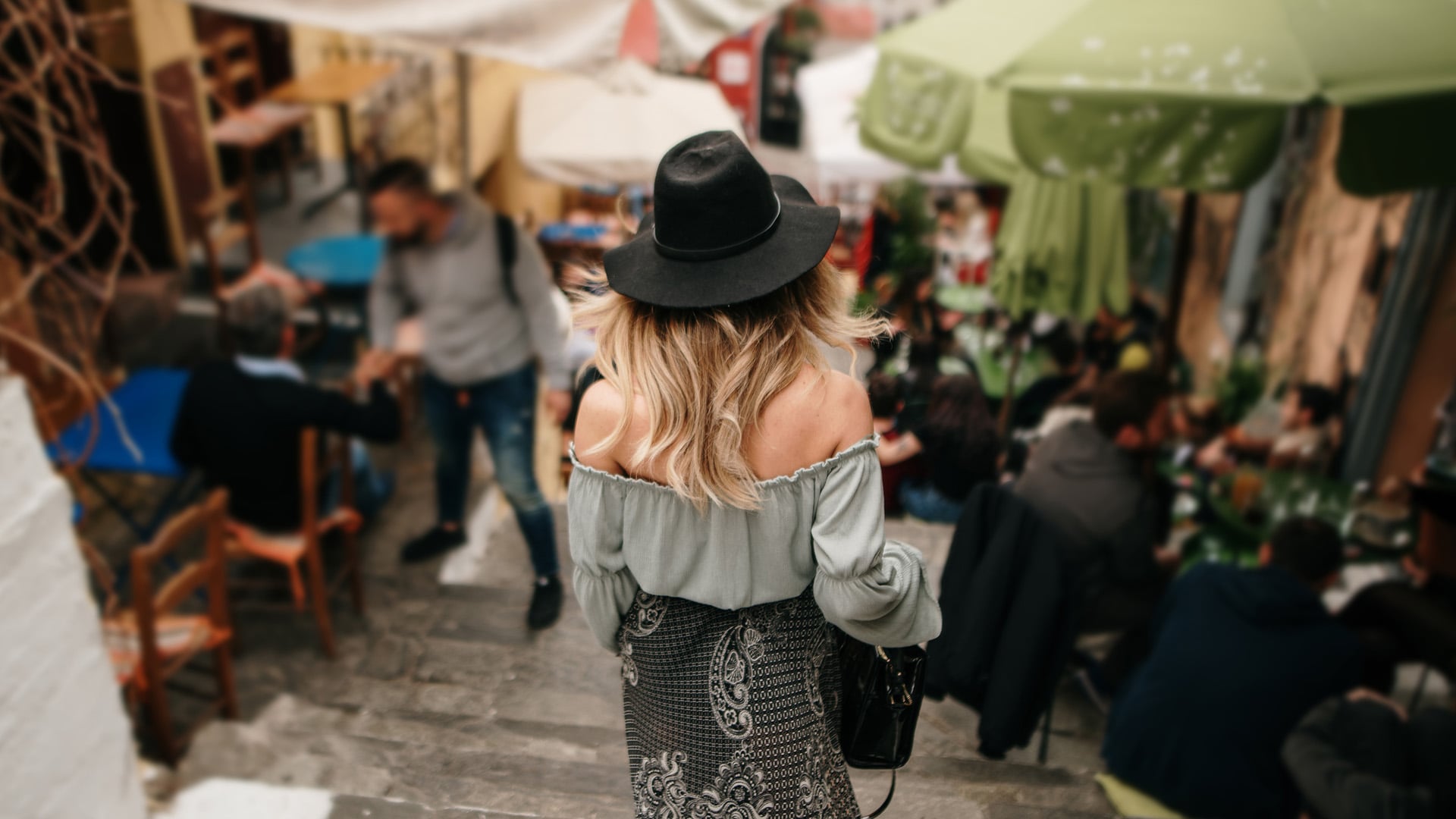 A woman walks down the steps of Plaka alongside restaurants in Athens, Greece