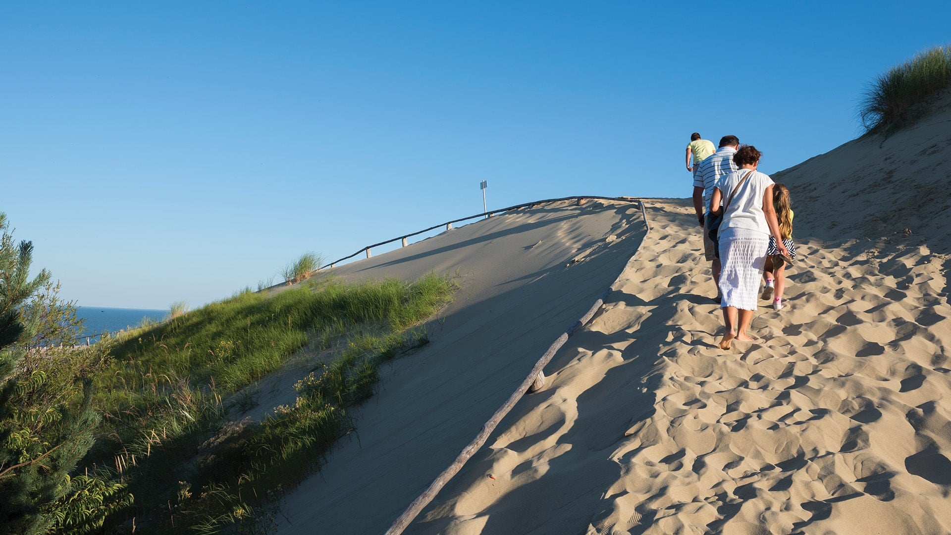 A group of people walking up a sand dune in Lithuania