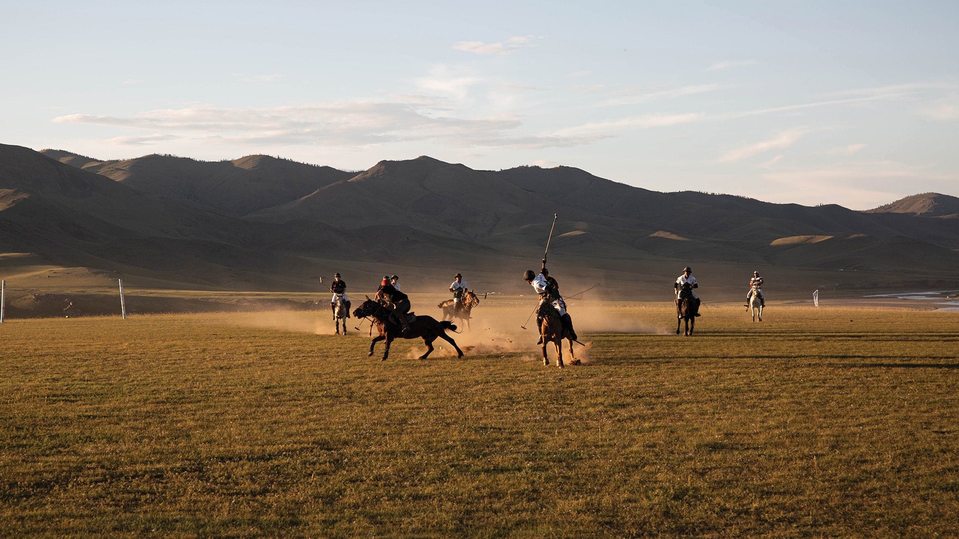 A group of people on horseback playing polo in front of a mountain range in the Orkhon Valley