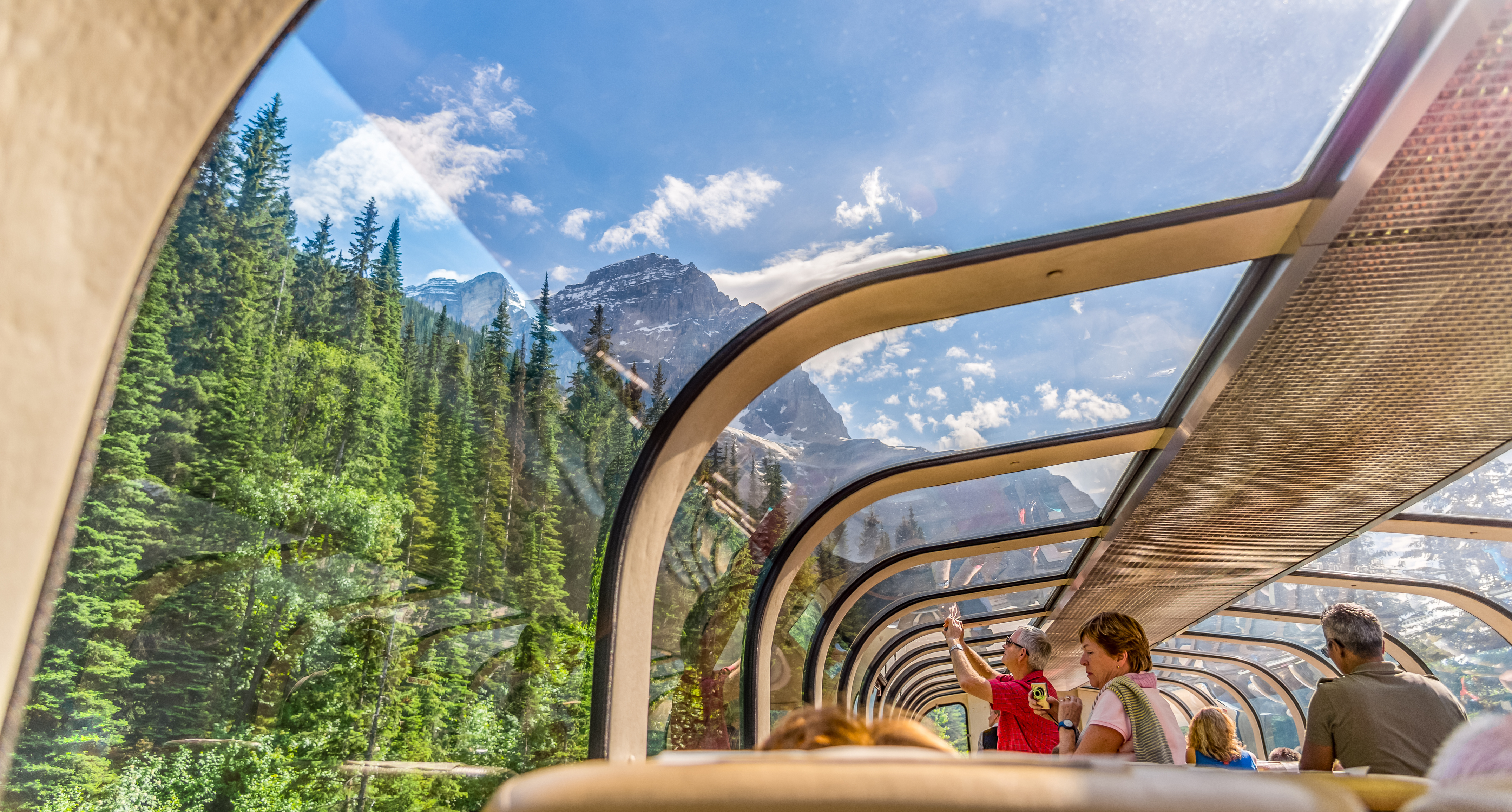 People inside the dome viewing platform of the Rocky Mountaineer train looking up to the sky and mountains through the glass, Rocky Mountains, Canada.
