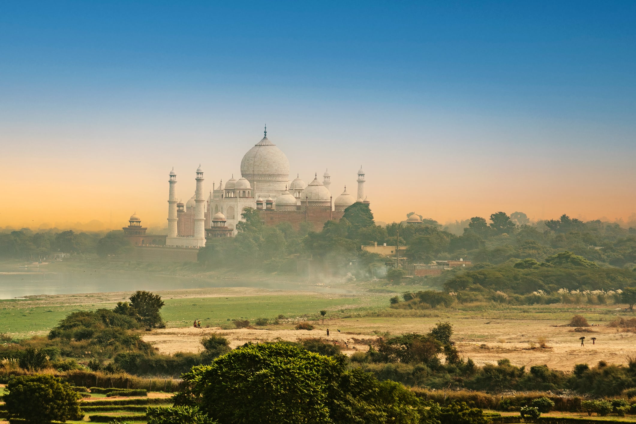 The Taj Mahal behind a gorgeous landscape at sunset in Agra, India.