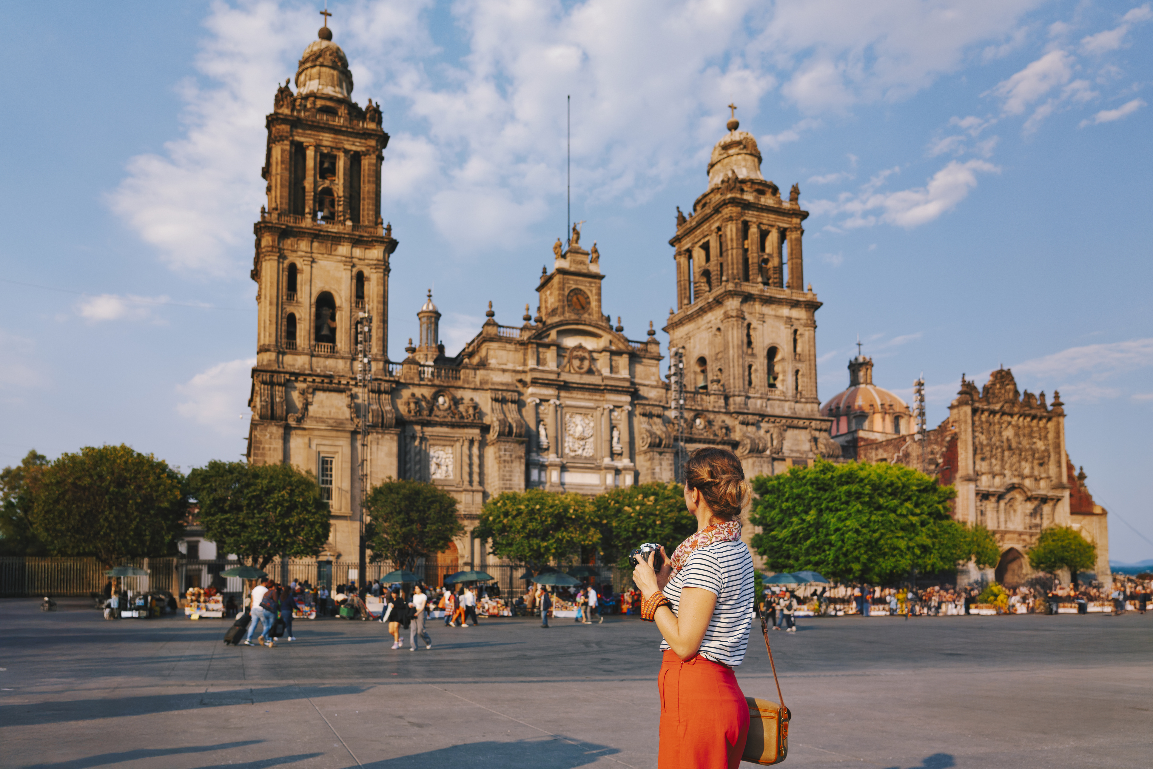 A young woman with a camera in hand looking at a cathedral in Mexico city, Mexico.