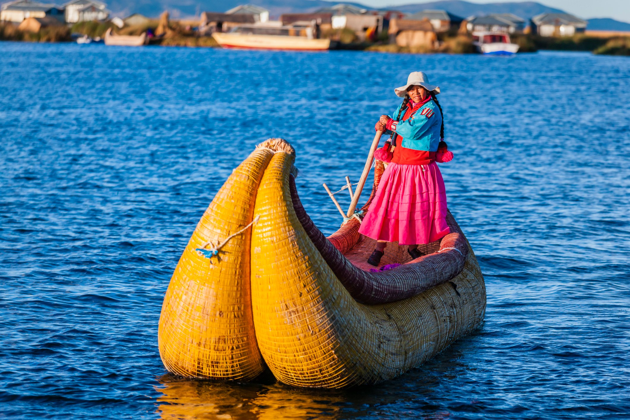 Peruvian woman sailing between Uros floating islands at Lake Titicaca, Peru.