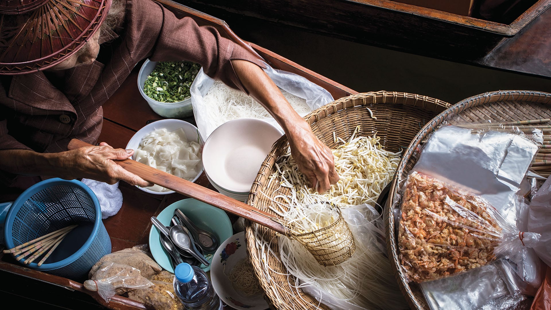 A woman makes boat noodles from her boat in Thailand.