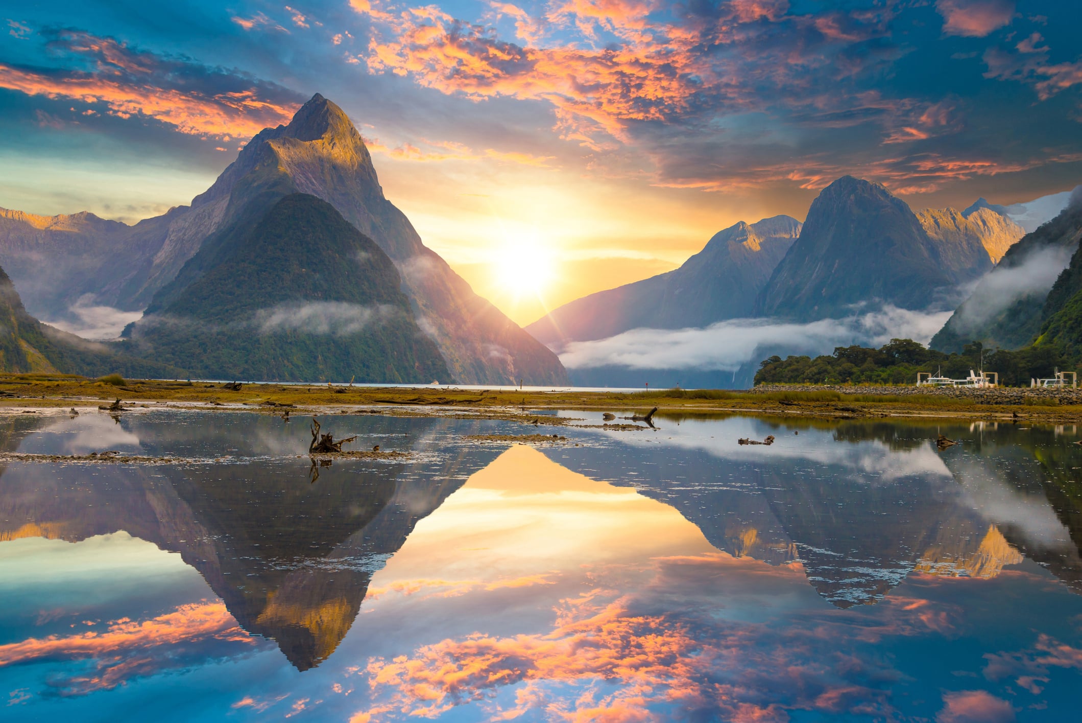 Milford Sound fiord in Fiordland national park, New Zealand, reflecting off of the lake at sunset.