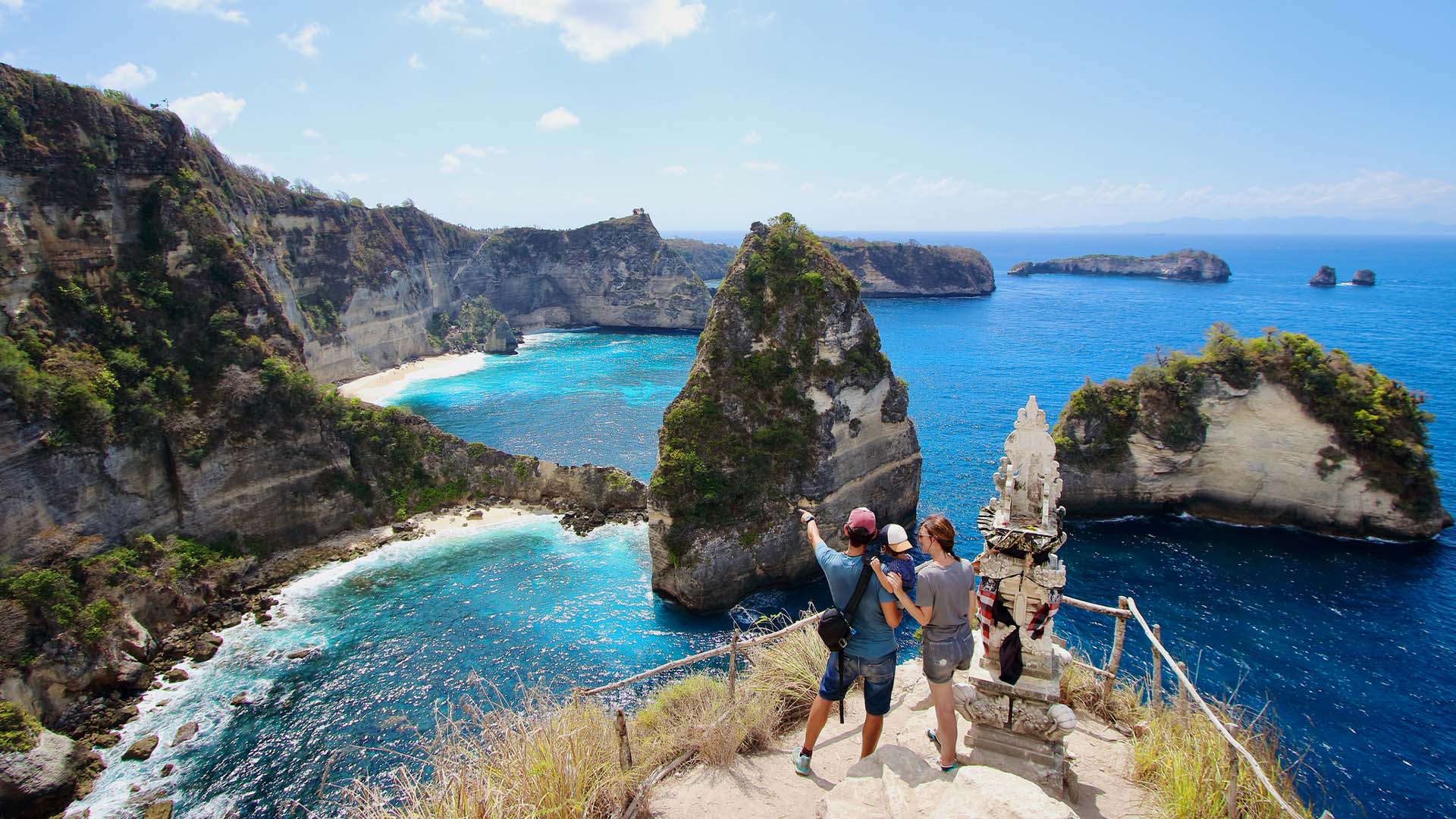 A mom and dad with their young kid looking out over Thousand Points Island on Bali.