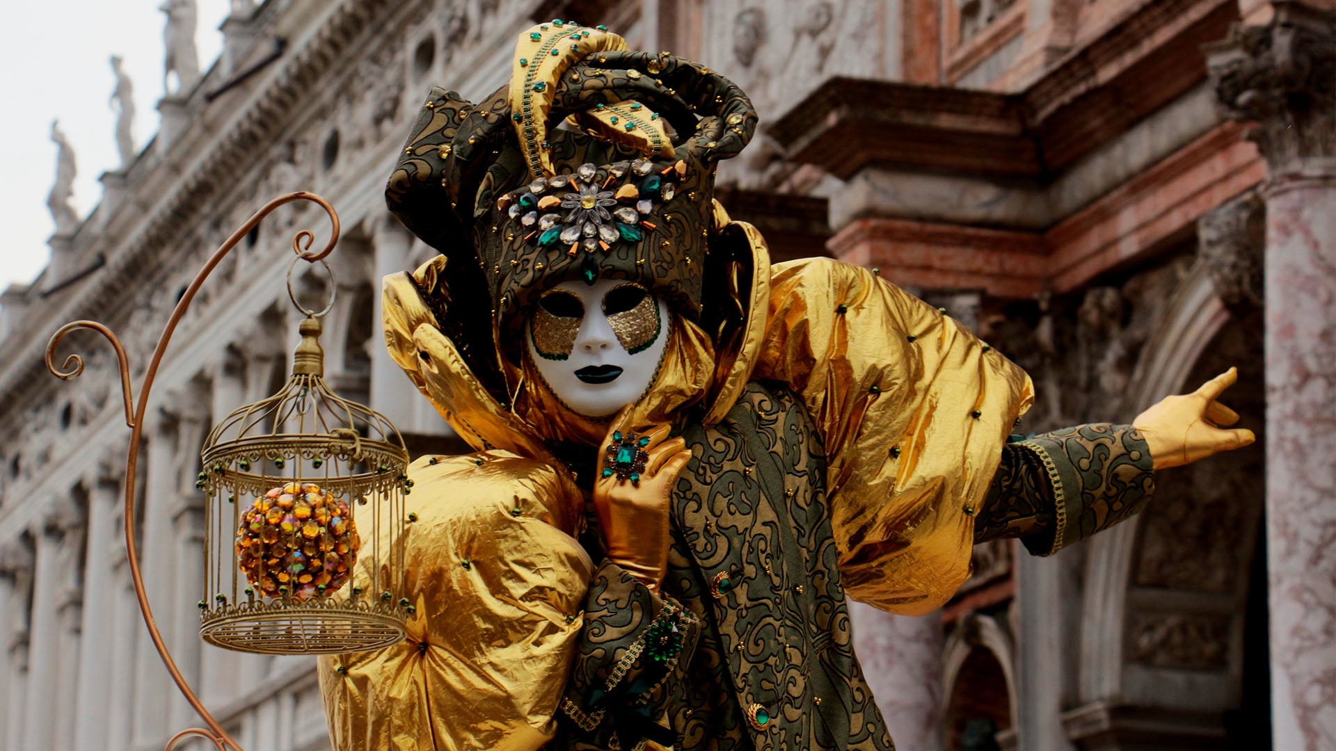 A person in an elaborate gold costume with a mask during Venice Carnival in Italy