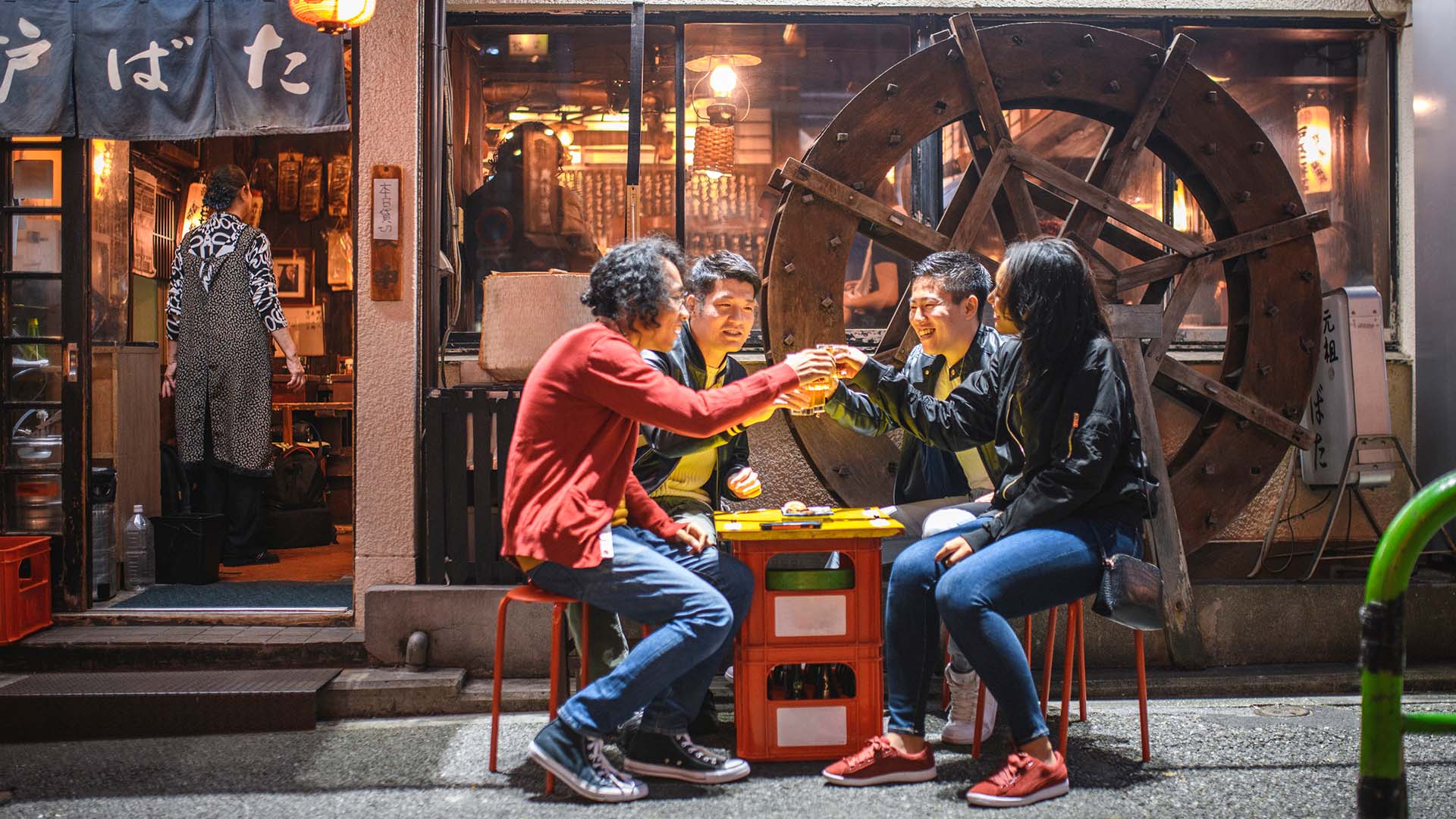 Four friends dine outside an izakaya in Tokyo, Japan