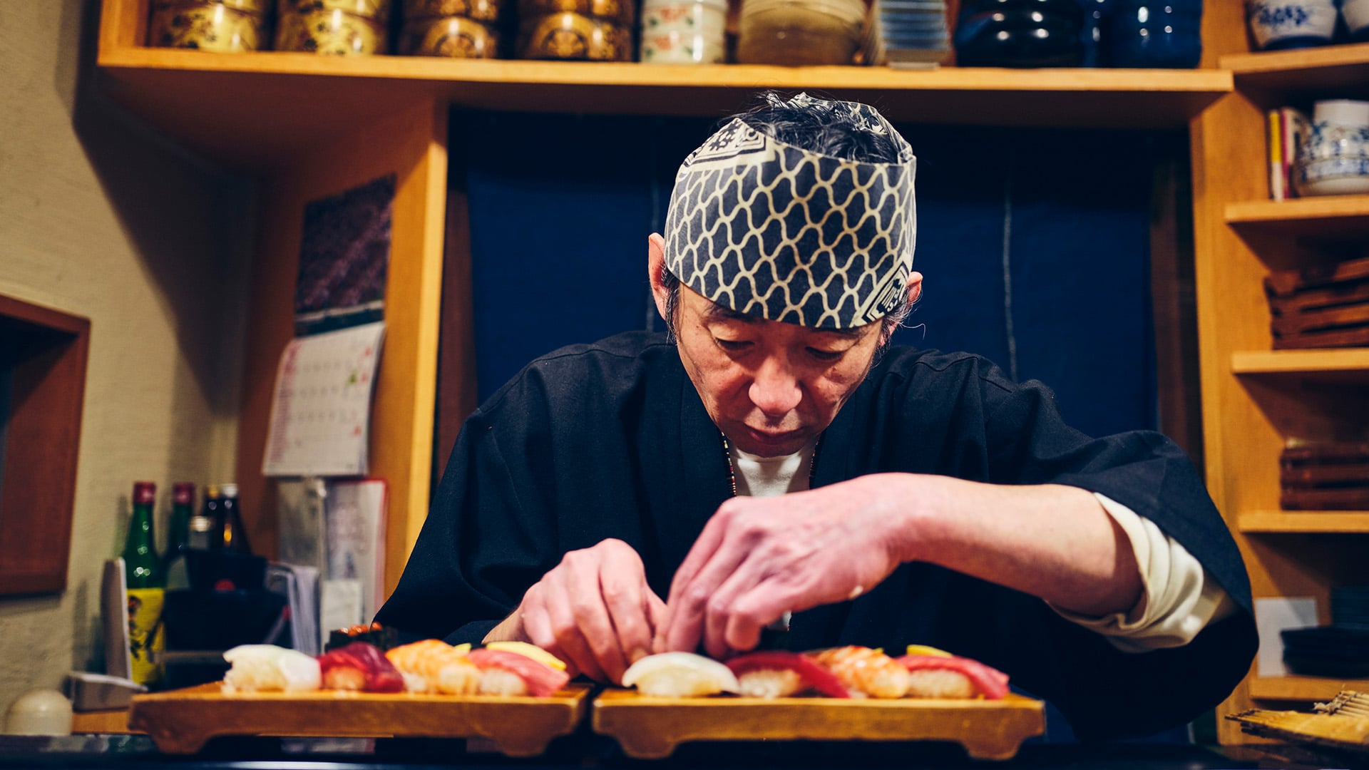A Japanese sushi chef carefully prepares a platter of nigiri sushi in Tokyo, Japan