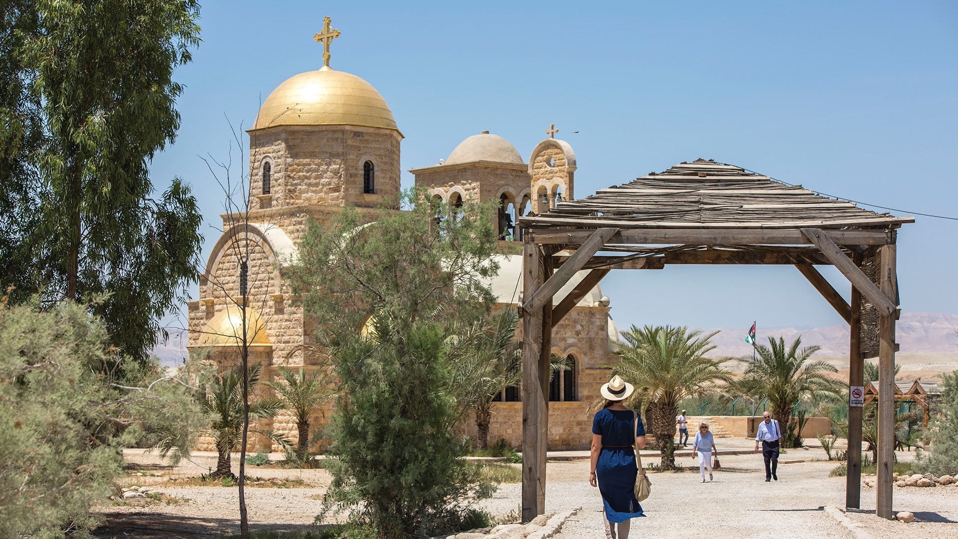 People walking underneath a wooden pavilion to and and from the St. John the Baptist Church 
