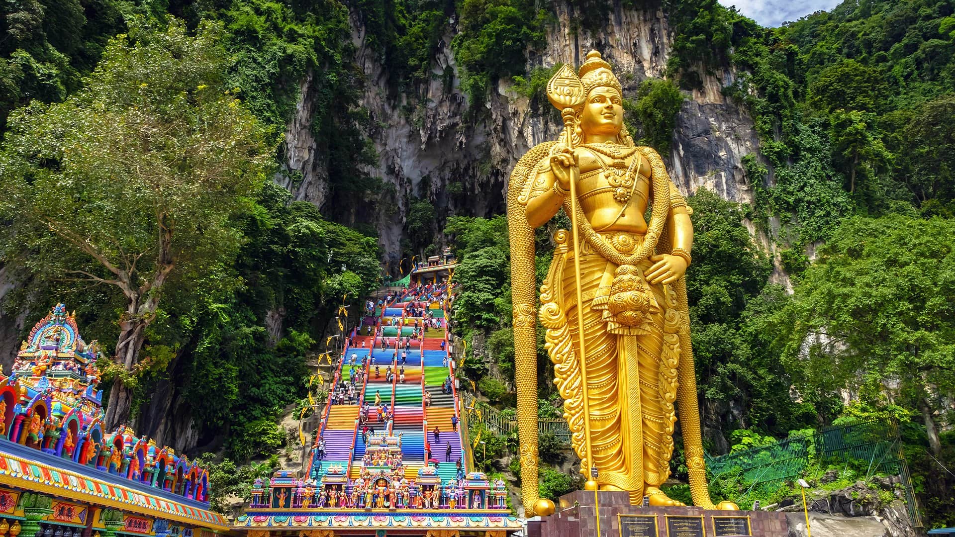 golden statue of a god against the backdrop of a lush mountain