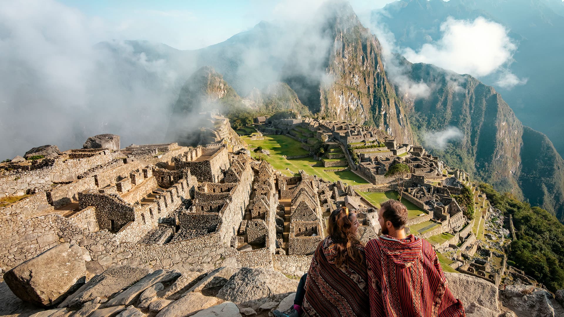 Two people sitting next to each other and overlooking Machu Picchu