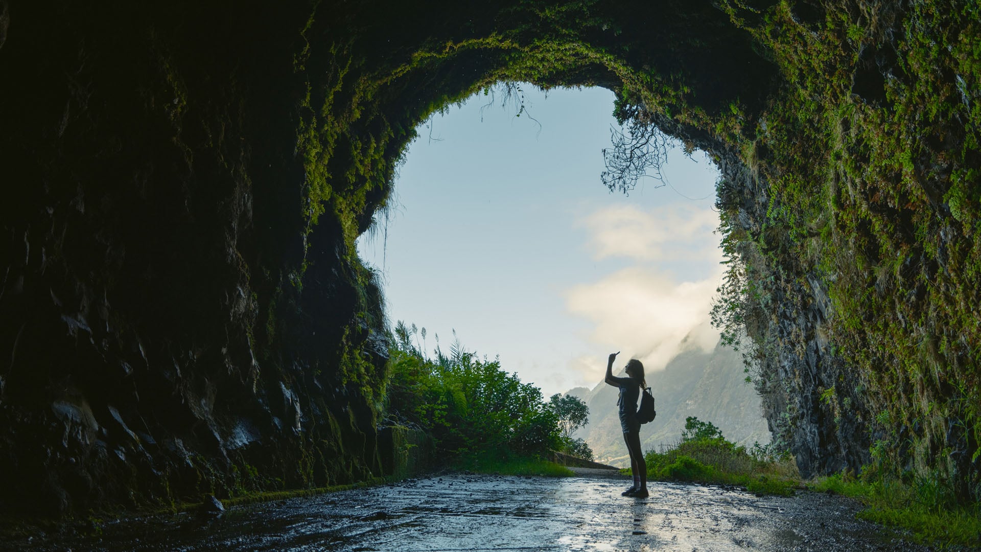 A woman stands taking a photo in a tunnel on Madeira in Portugal