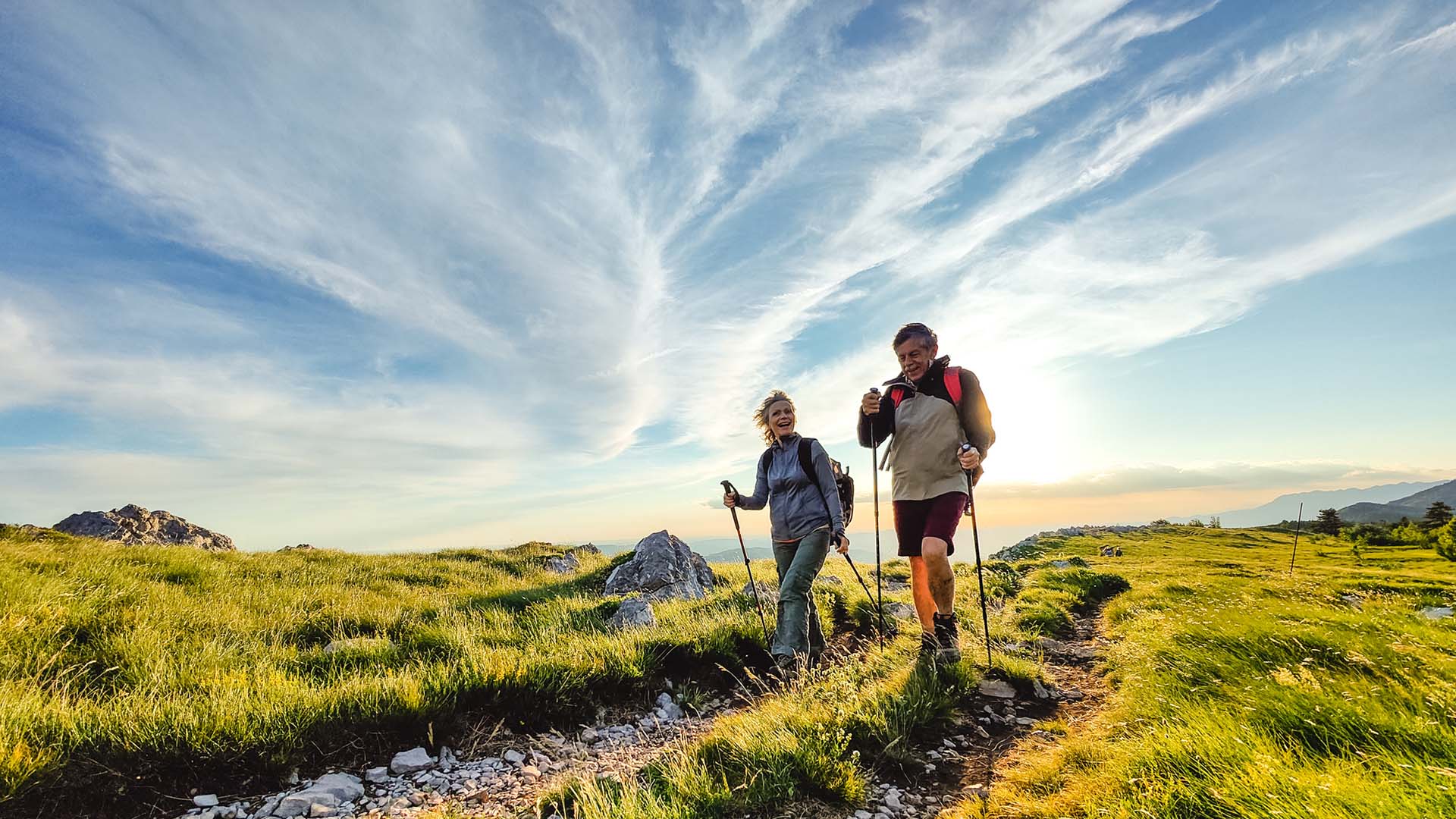 An older couple Nordic walking with ski poles through the Slovenian wilderness.