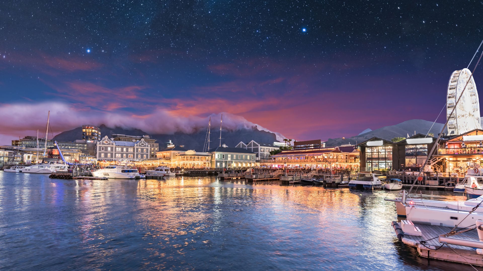 The V&A Waterfront in Cape Town at night with stars in the night sky.