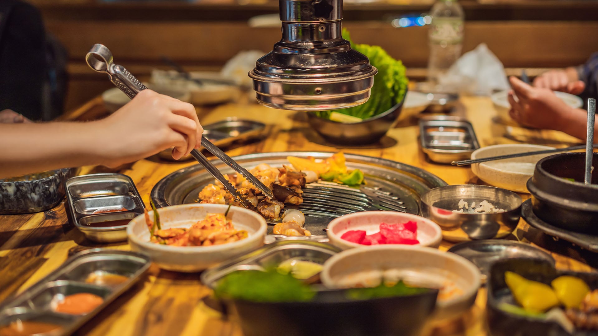 Woman grilling barbecue on mesh grill of charcoal fire. Korean or japanese traditional food grilling style barbecue