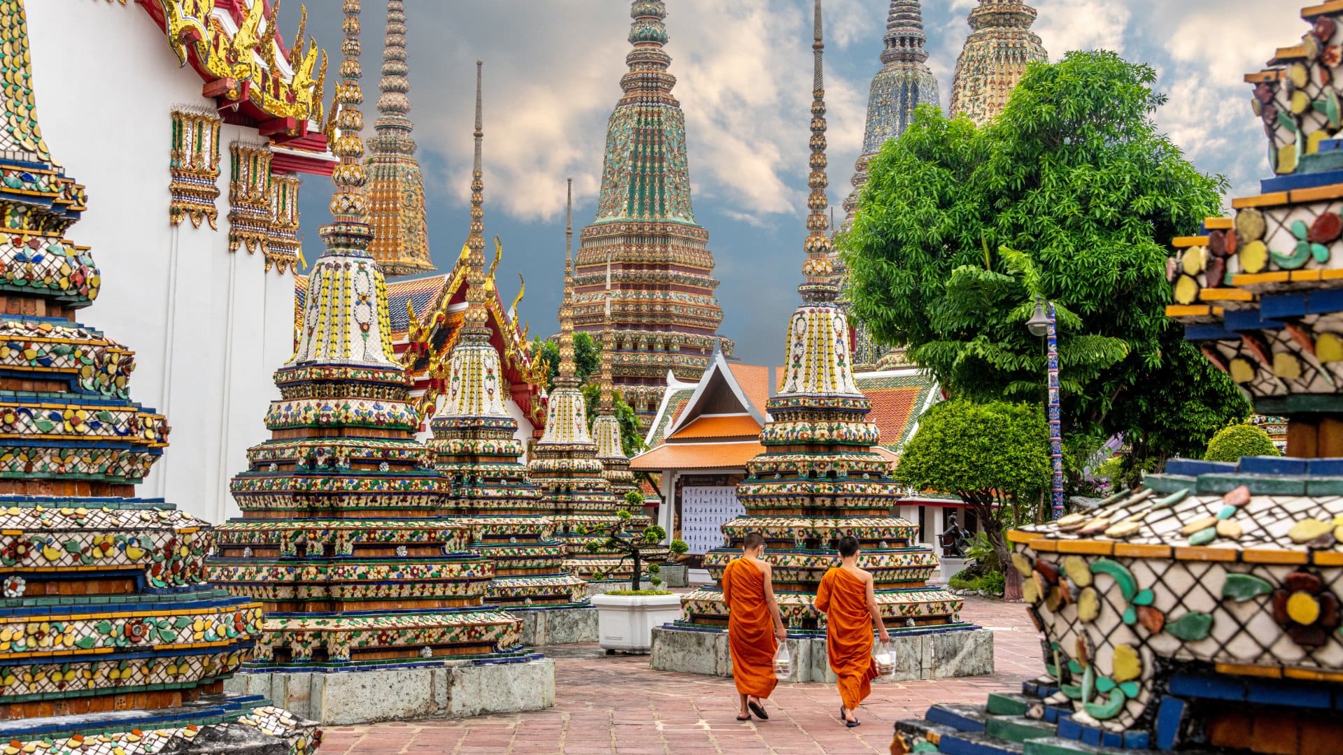 Two monks walk alongside the stupas at Wat Pho in Bangkok, Thailand.