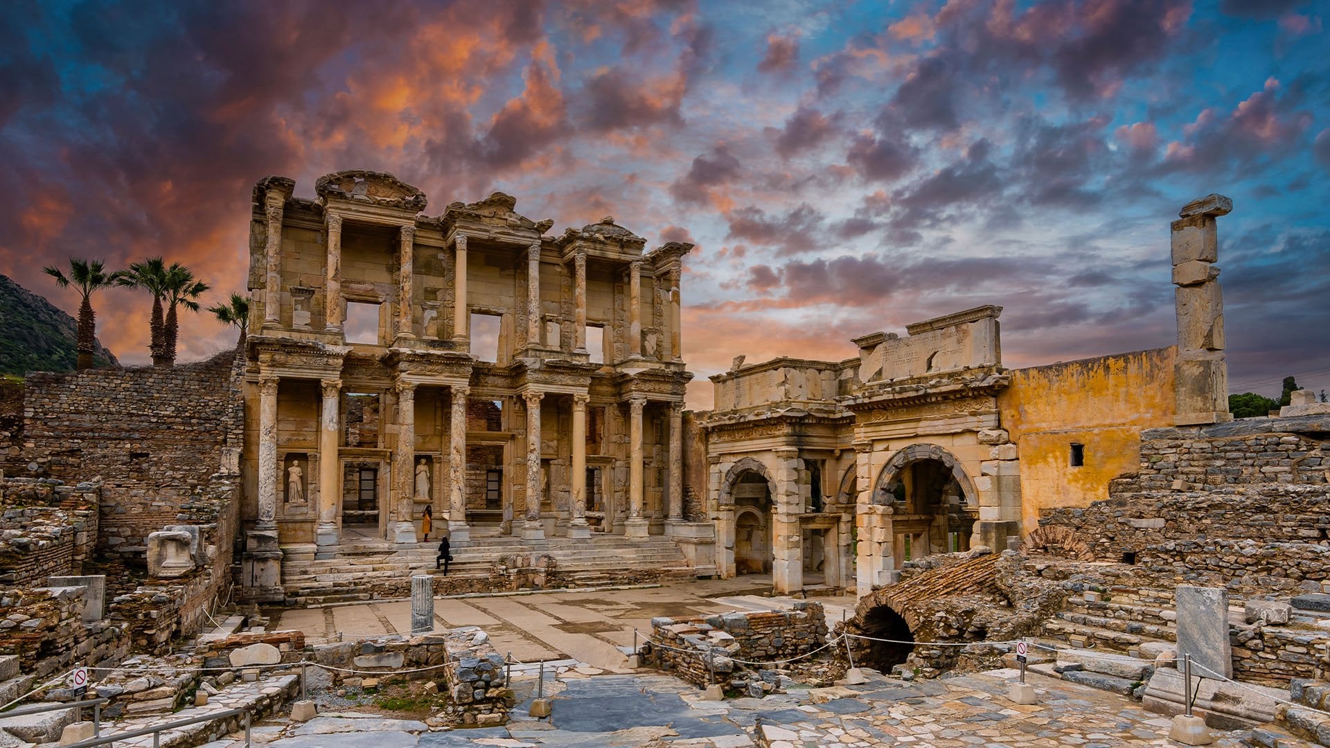 old Roman ruins and columns stand beneath a startling sunset in Ephesus