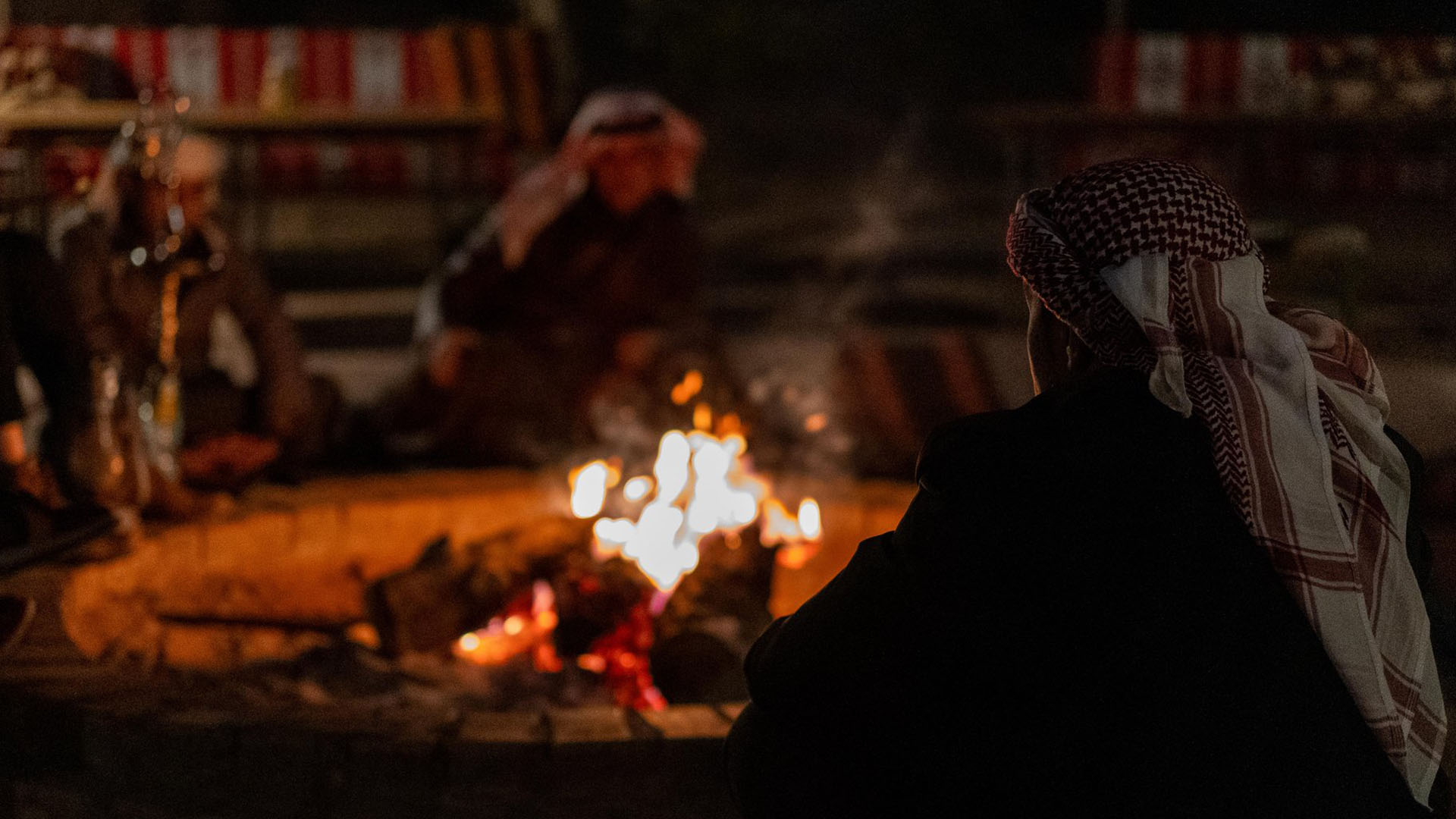 A group of Jordanian men huddling around a fire.