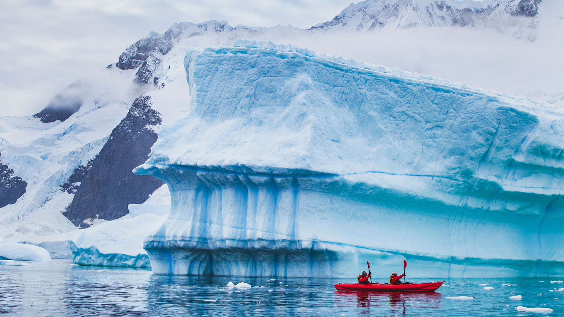 Two people kayaking through the waters of Antarctica.