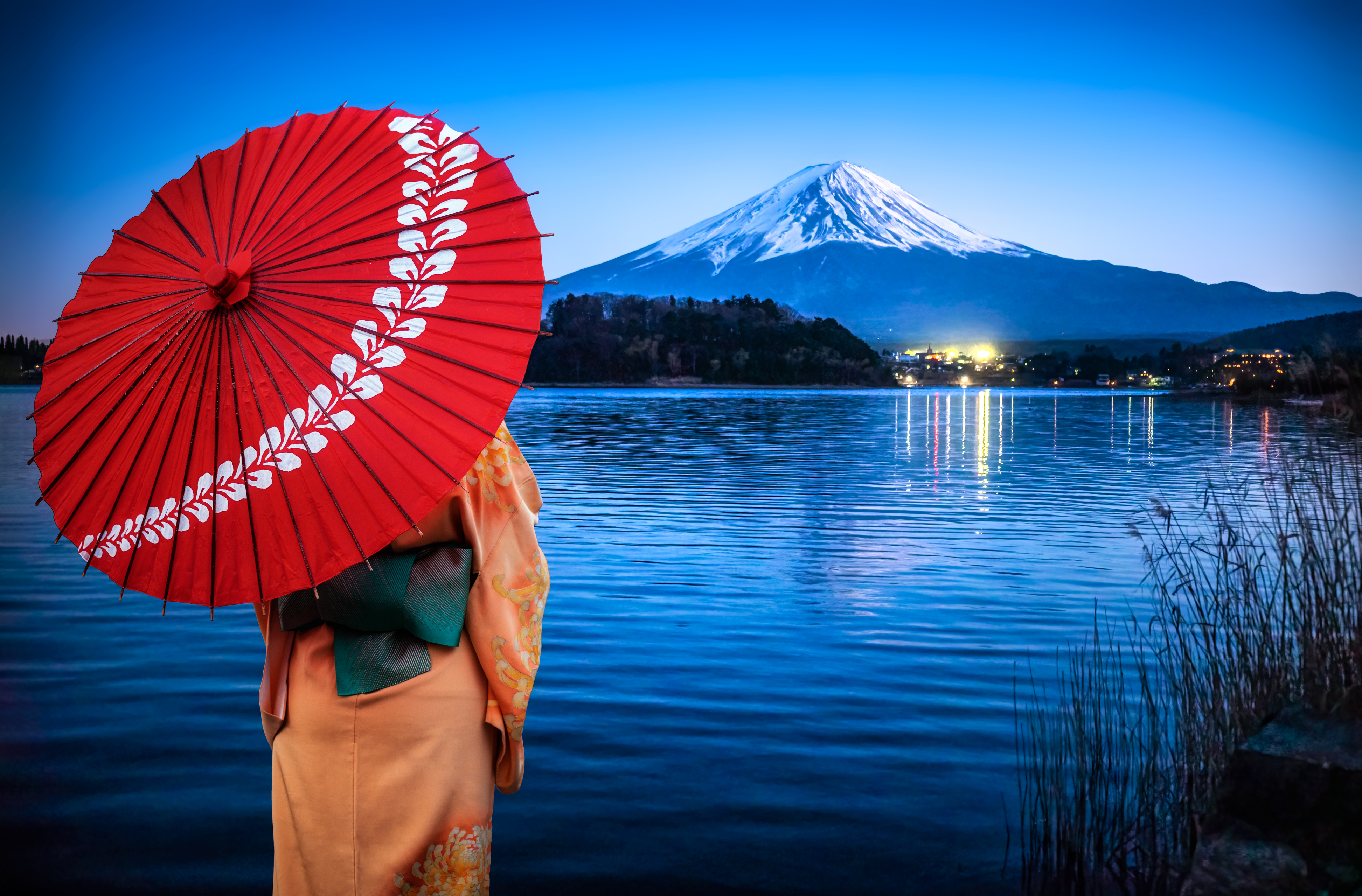 Woman enjoying the view of Mount fuji at night reflected on Lake Kawaguchi