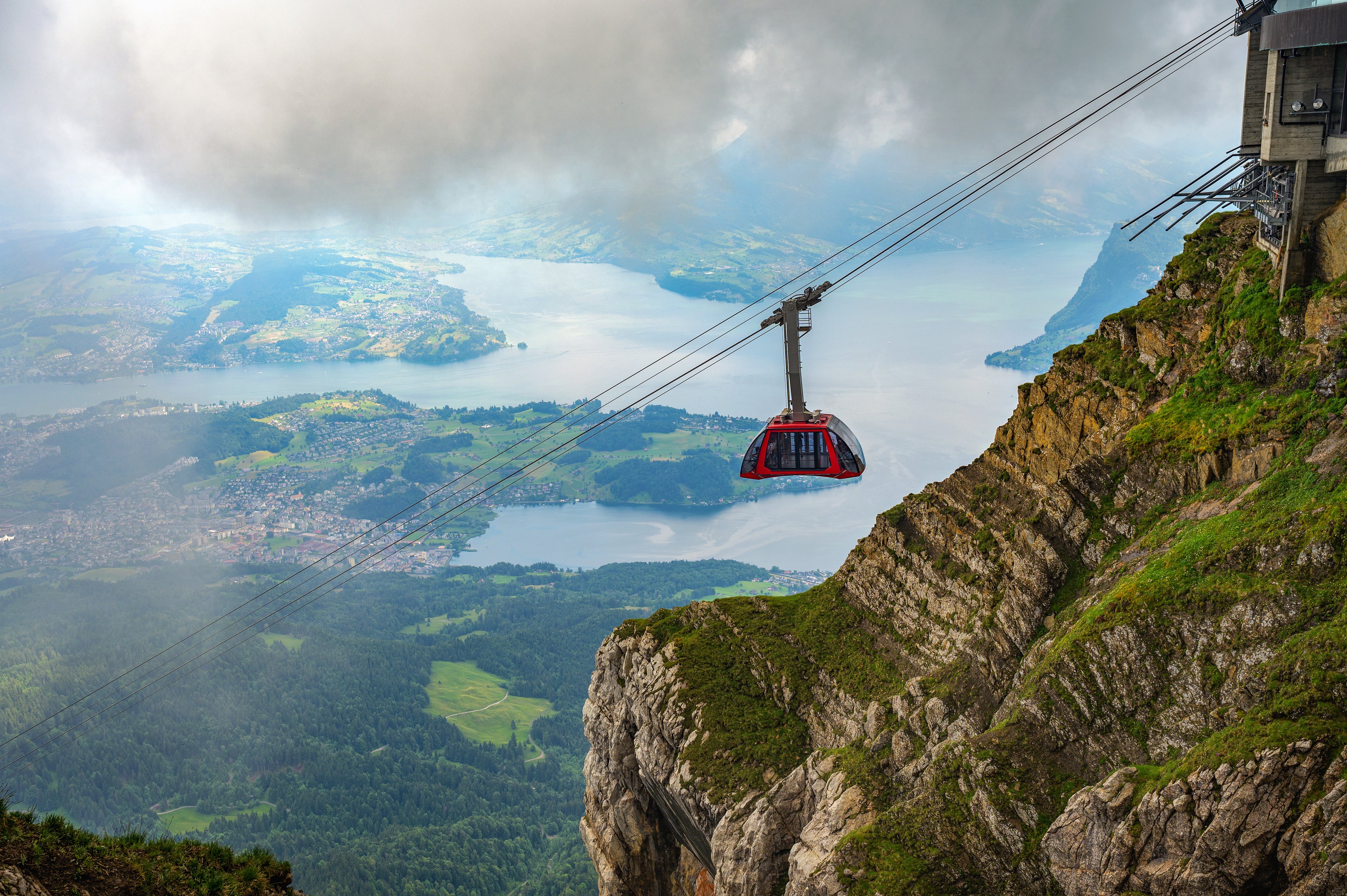Mount Pilatus, Lucerne, Switzerland Cable car approaching Mount Pilatus in Switzerland, with Lake Lucerne visible in the background amidst fog and clouds.