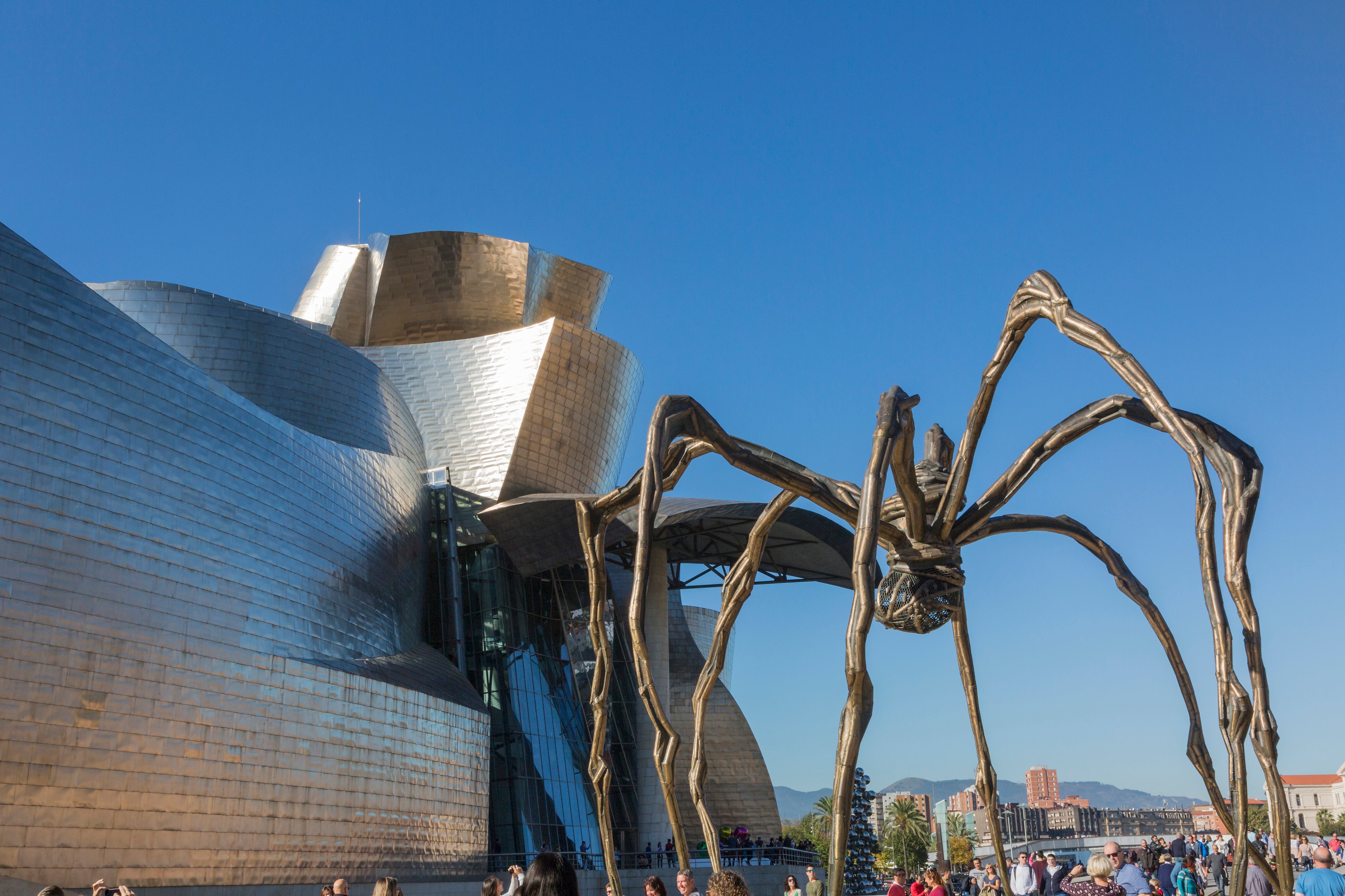 Back of the Guggenheim Museum, contemporary art, work of the Canadian architect Frank O. Gehry, and the sculpture of the spider of Louise Bourgeois. There are people walking