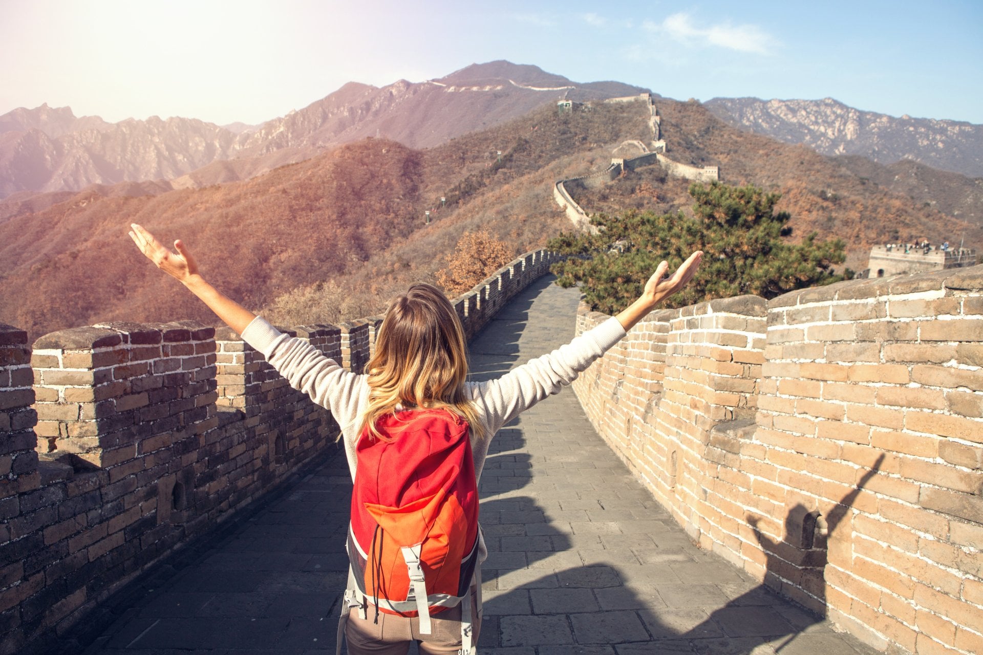 Young woman on top of the Great Wall of China arms outstretched for freedom and positive emotions