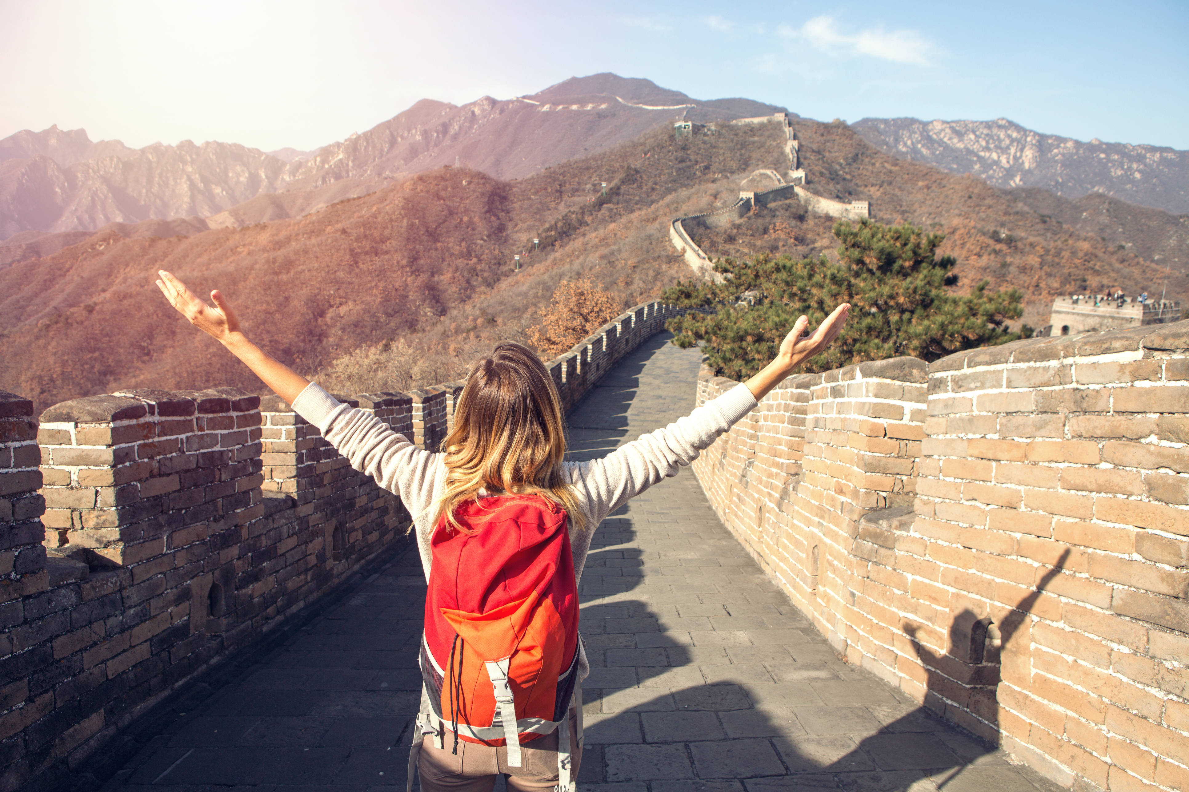 Young woman on top of the Great Wall of China arms outstretched for freedom and positive emotions